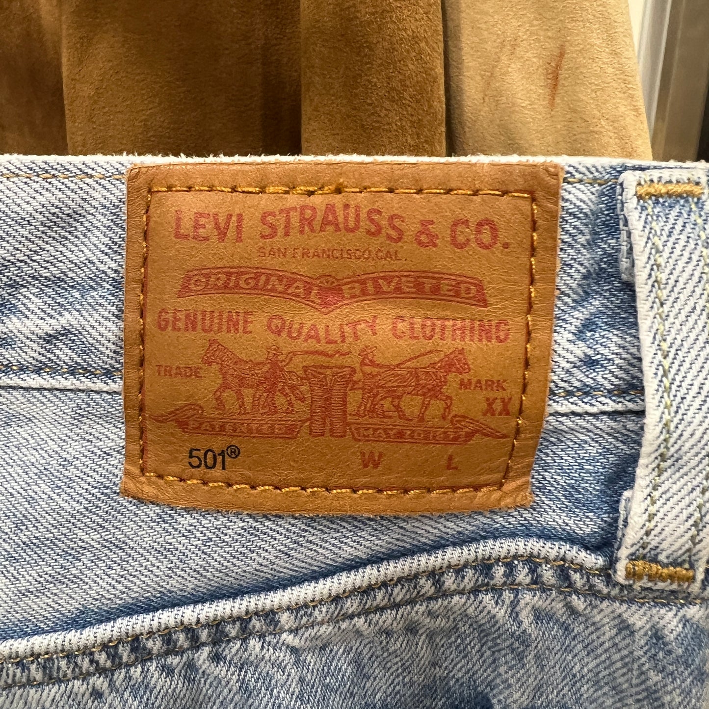 Light-wash Levi’s 501 jeans with classic brown leather patch featuring the Levi Strauss & Co. Two Horse logo, photographed close-up on the waistband
