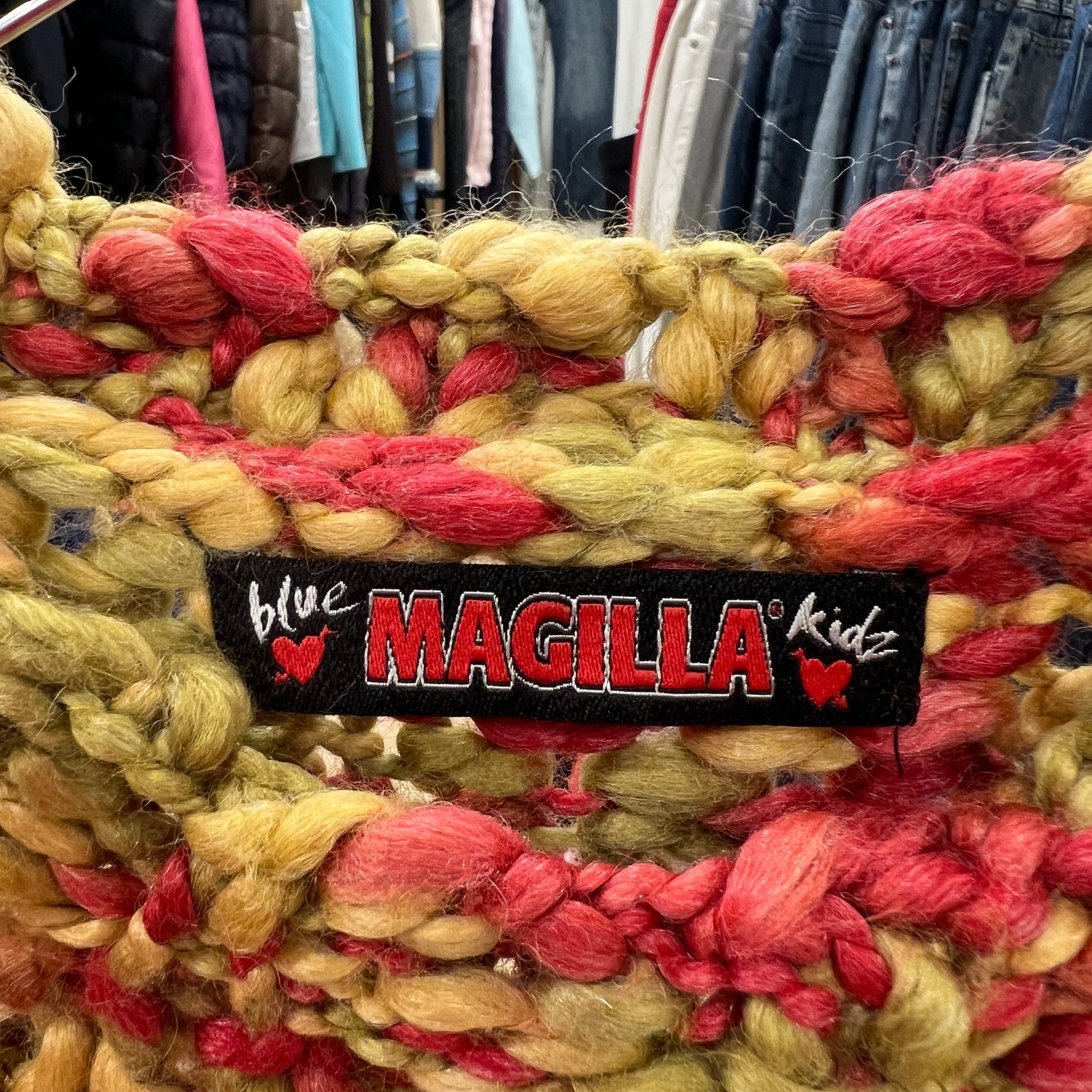 Colorful yarn with a 'blue MAGILLA Kidz' label in a clothing store setting