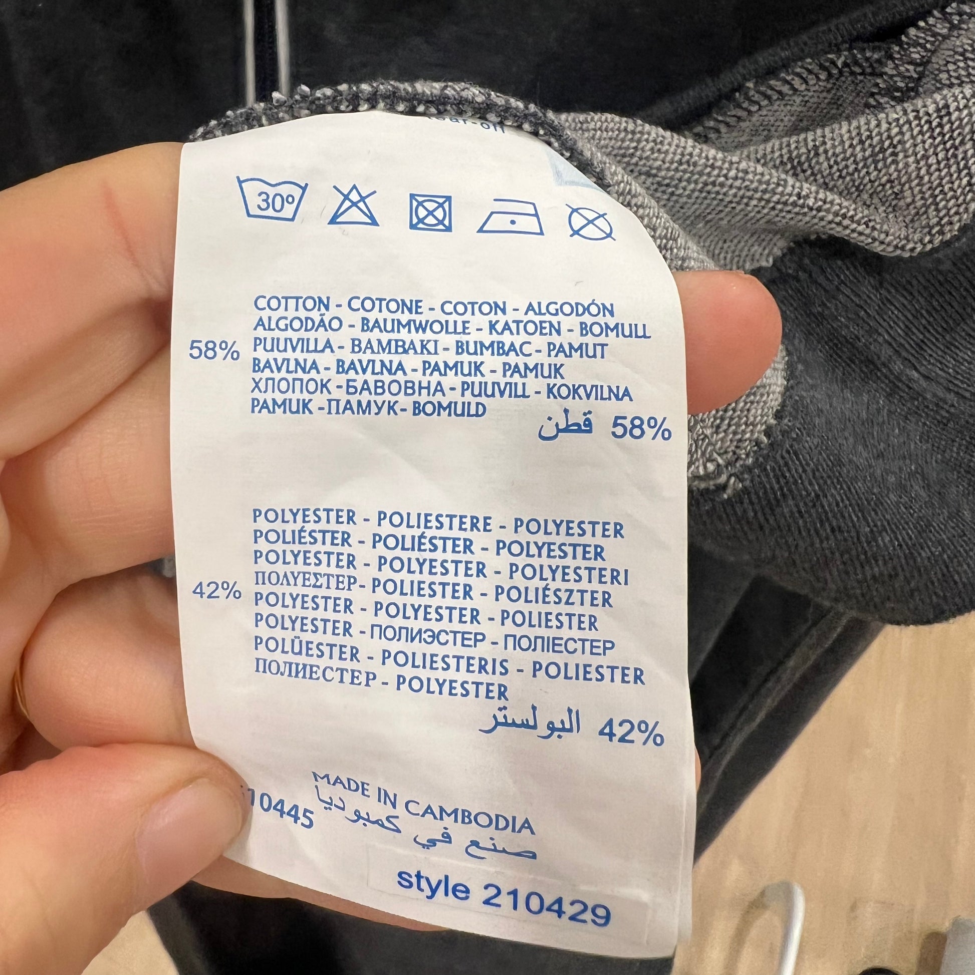 Clothing label with fabric composition details held by a hand