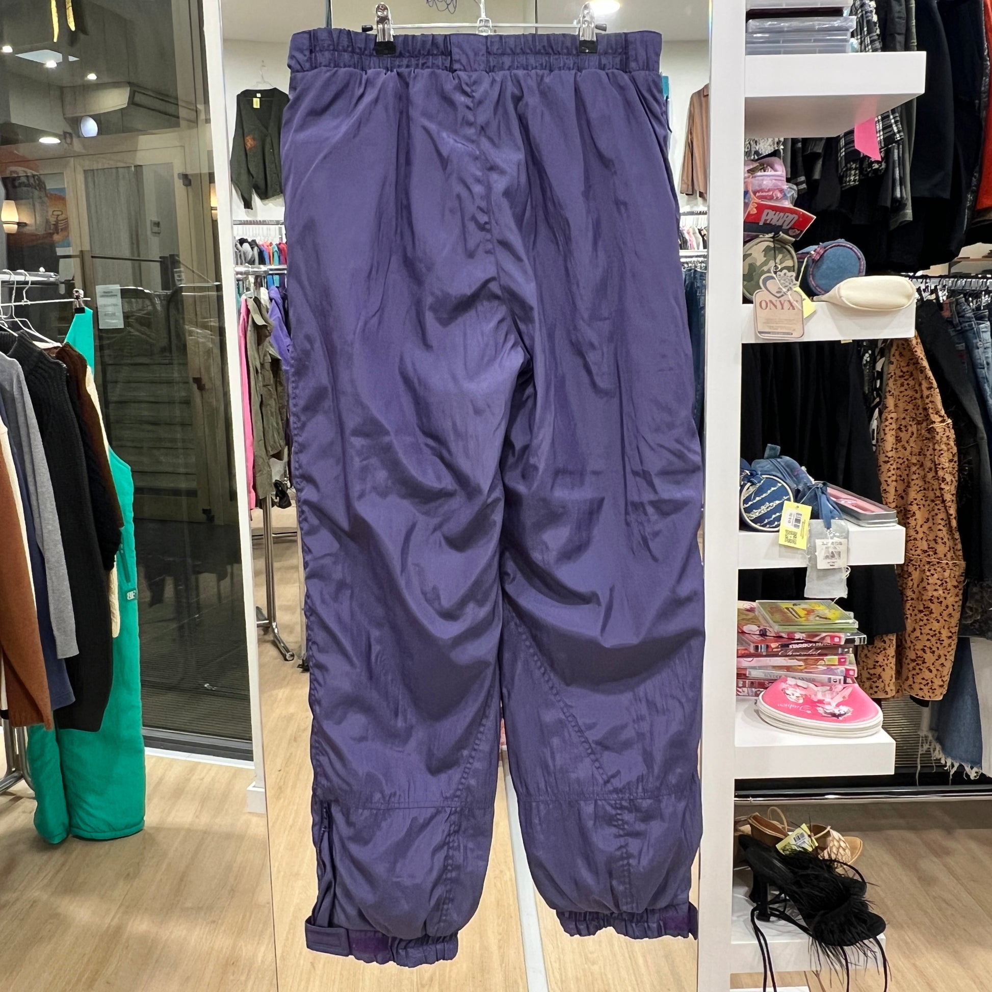 Purple pants hanging in a store with clothing racks and shelves in the background