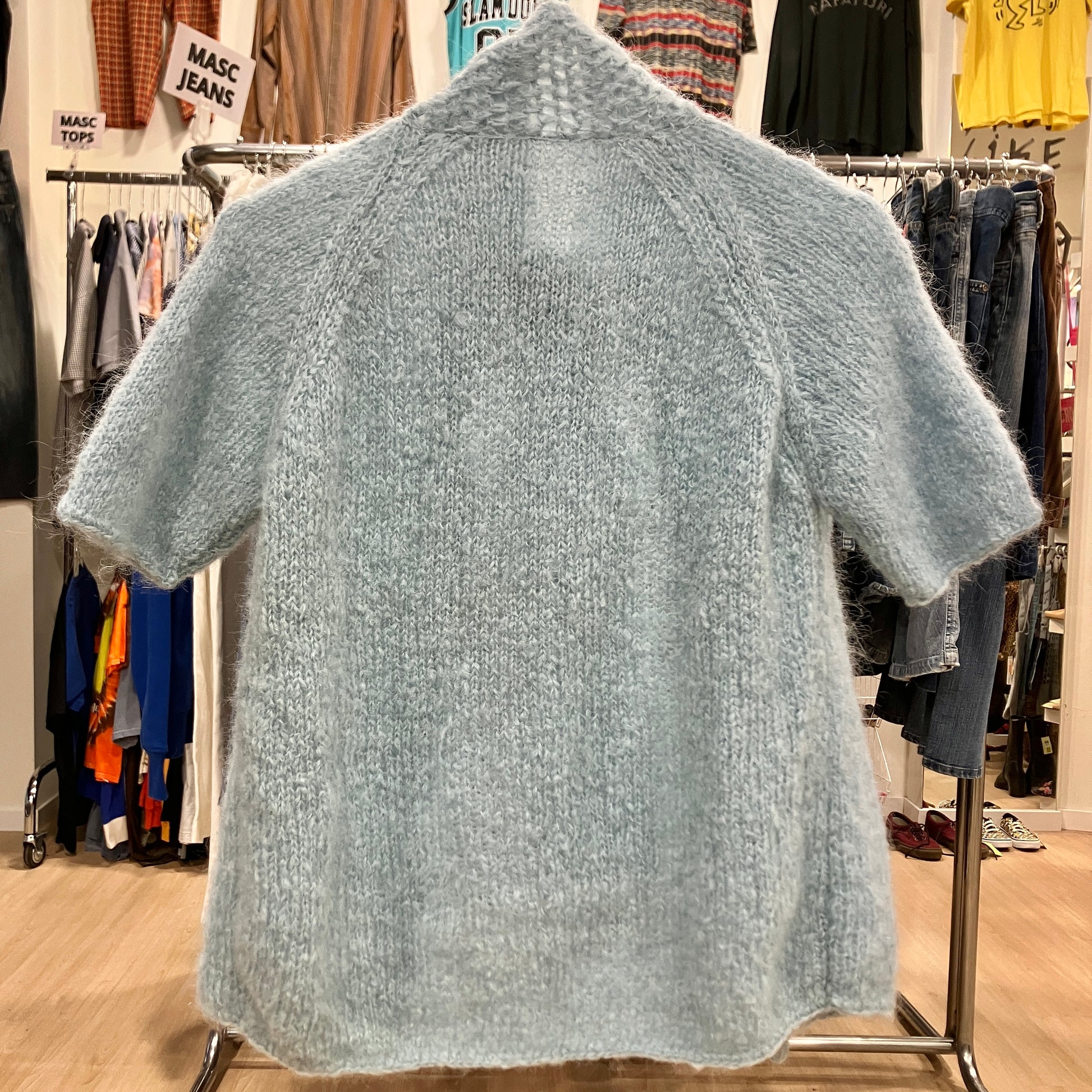 Light blue knitted sweater on a hanger in a clothing store
