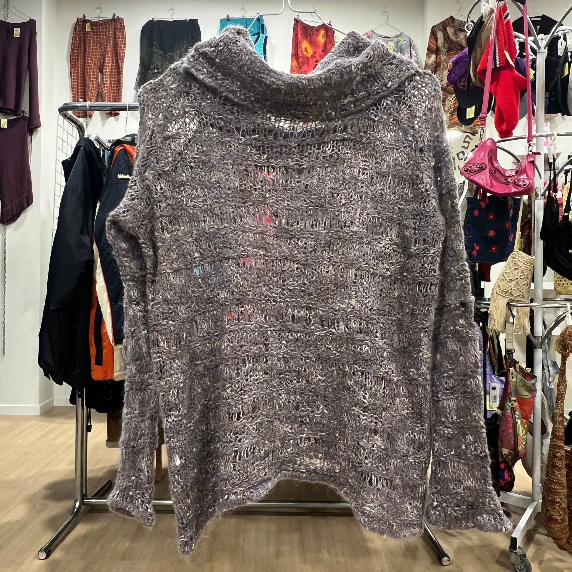 Gray textured sweater on a hanger in a clothing store setting