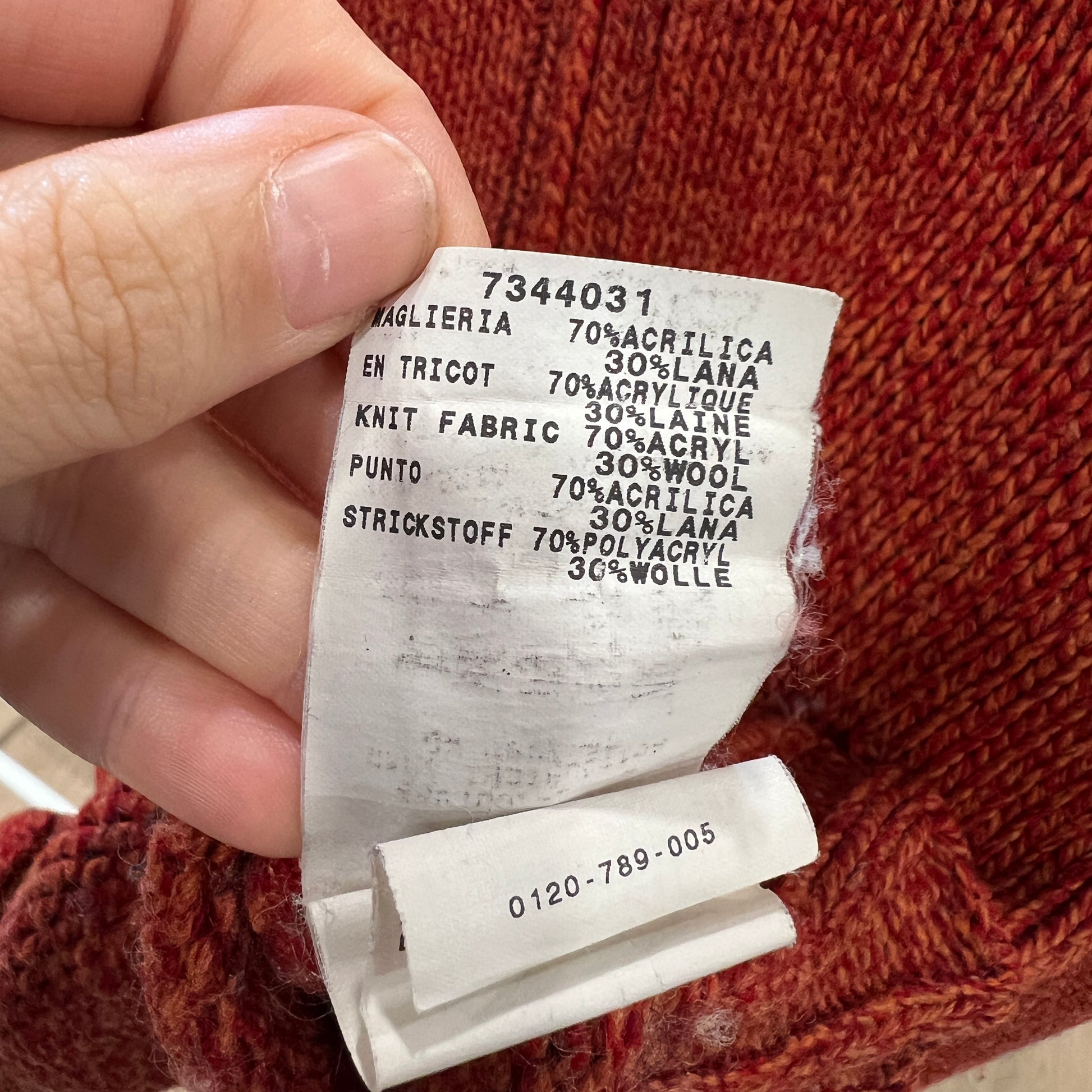 Close-up of a fabric label held over a knitted item with text on it