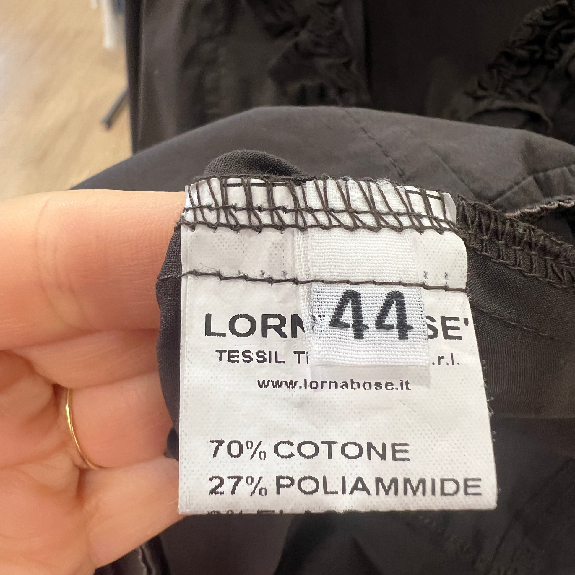 Clothing label with brand name and size information on a black garment