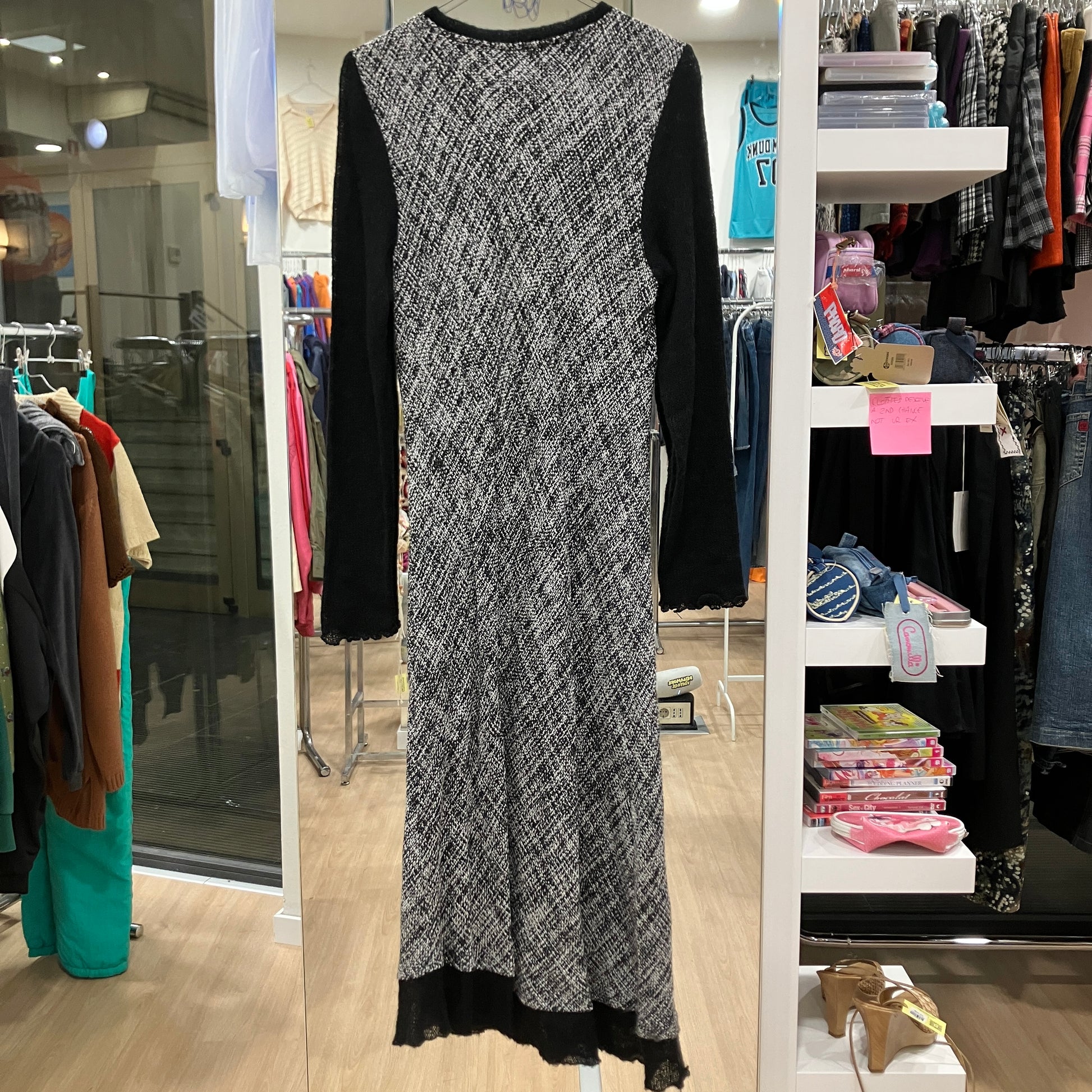 Long black and white patterned dress displayed in a store setting with shelves and clothing racks