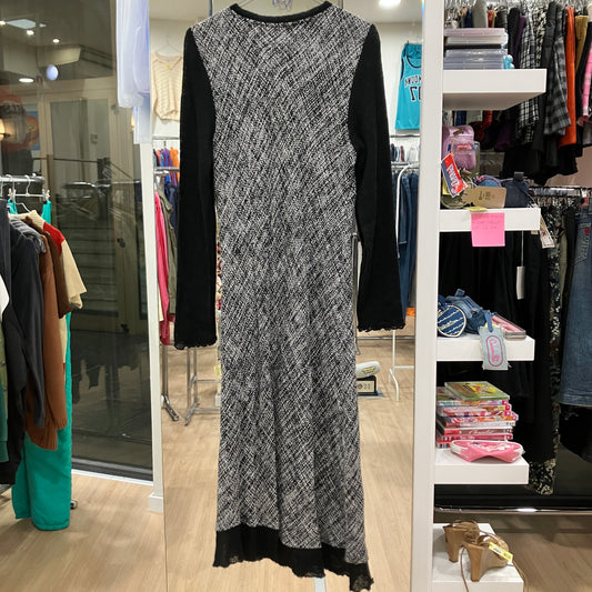 Long black and white patterned dress displayed in a store setting with shelves and clothing racks