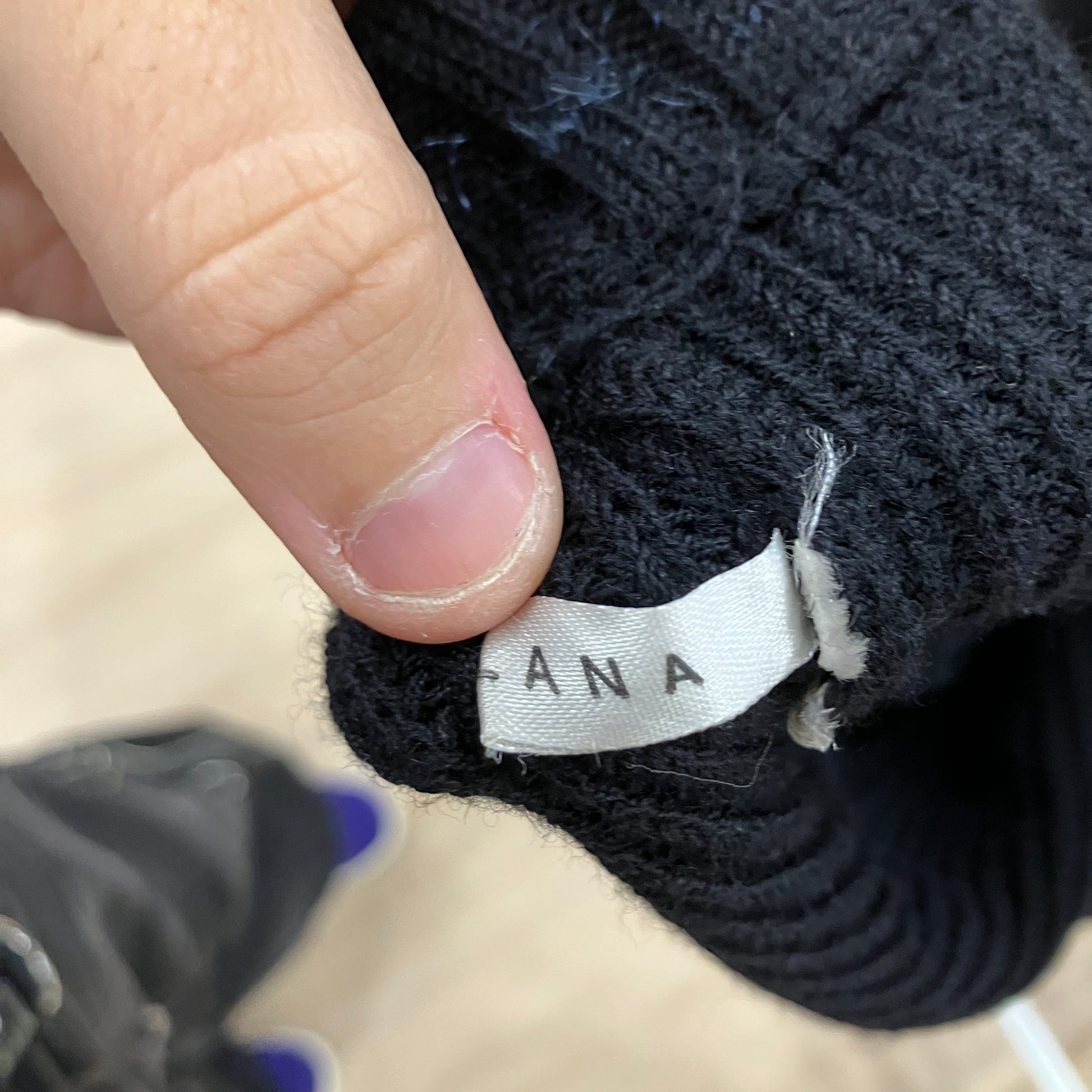 Close-up of a black textured product with a visible brand label, held by a finger