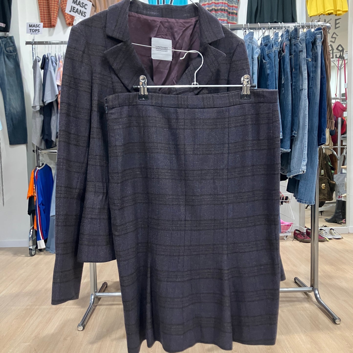 Dark brown plaid suit on a hanger with a clothing store background