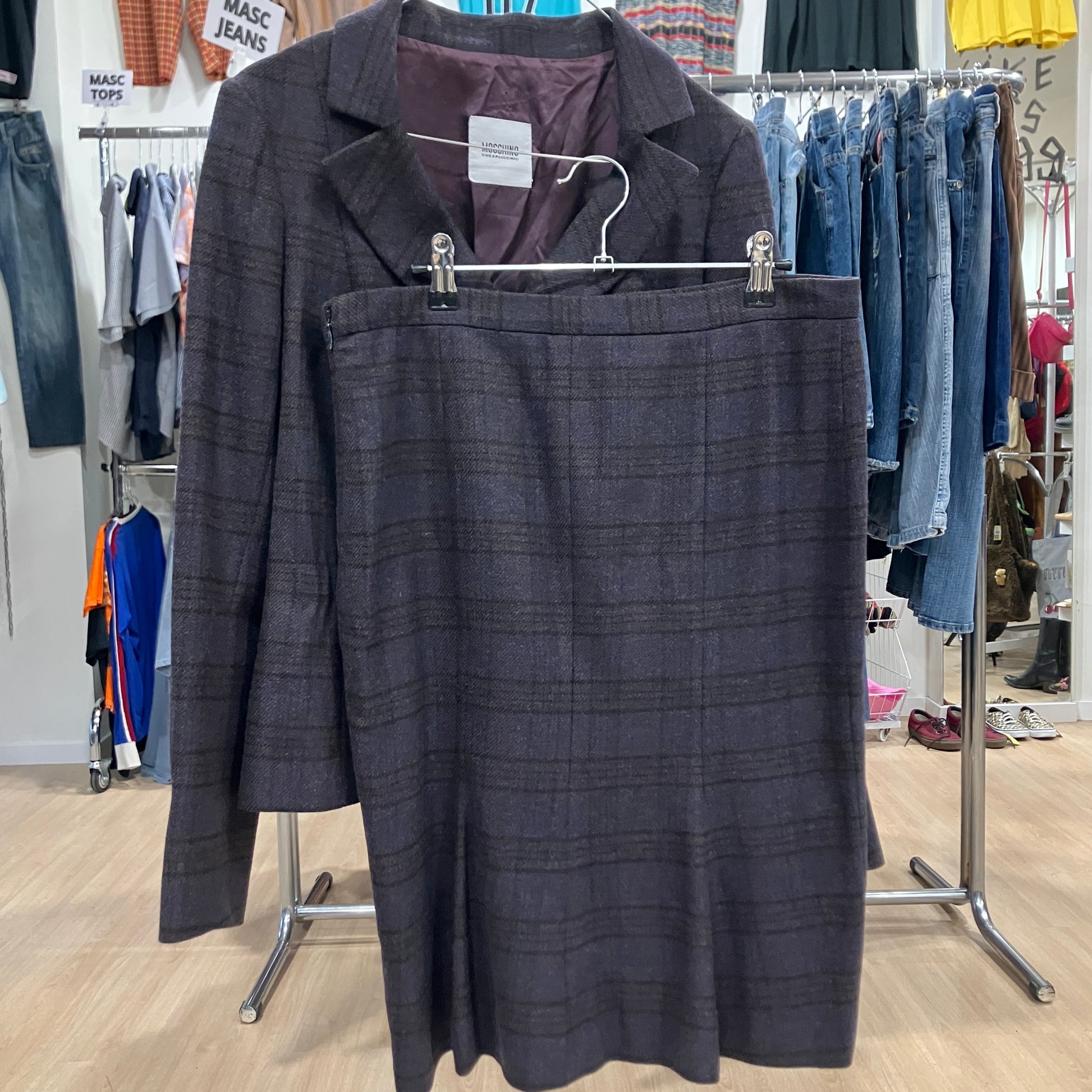 Dark brown plaid suit on a hanger with a clothing store background
