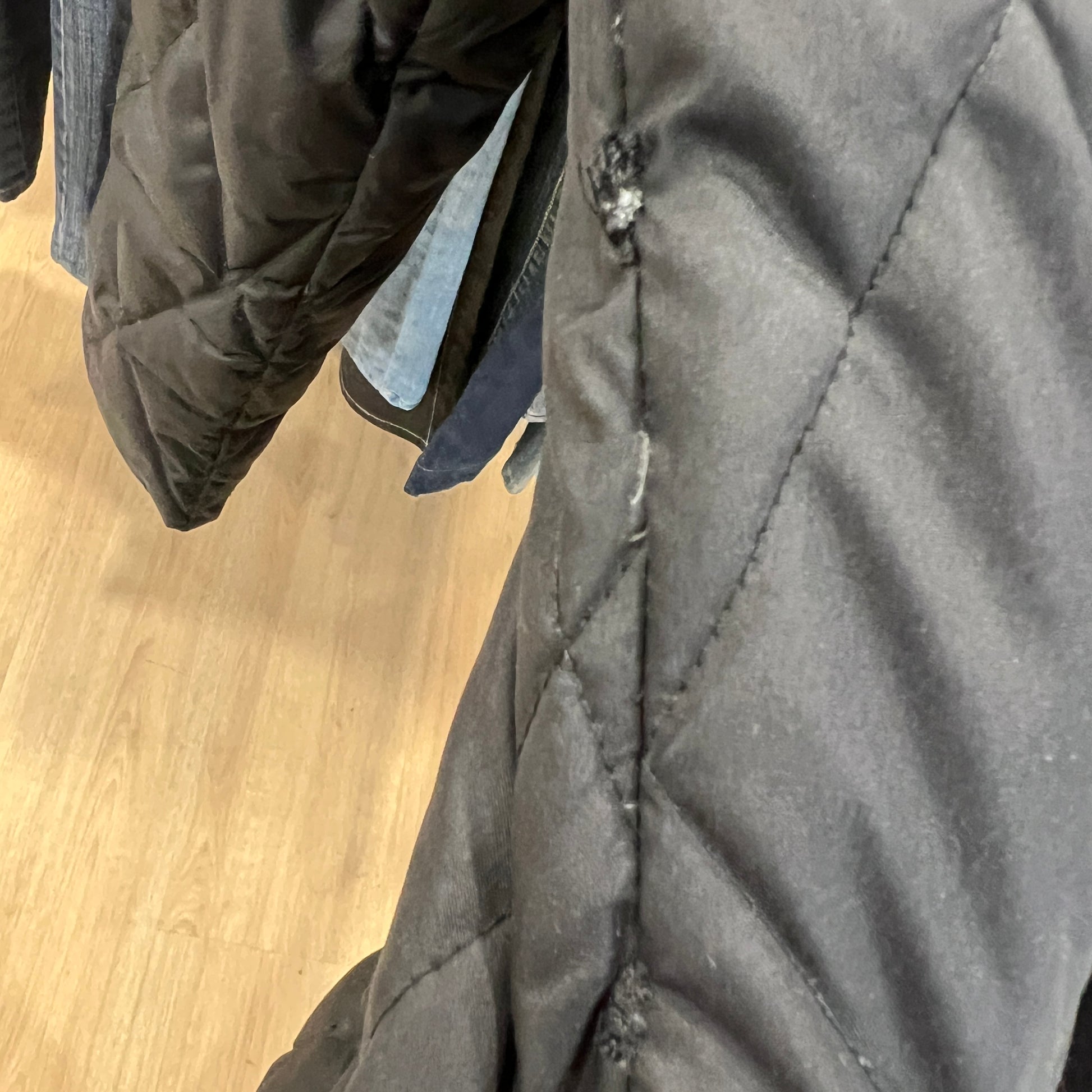 Close-up of a gray quilted jacket with a wooden floor in the background