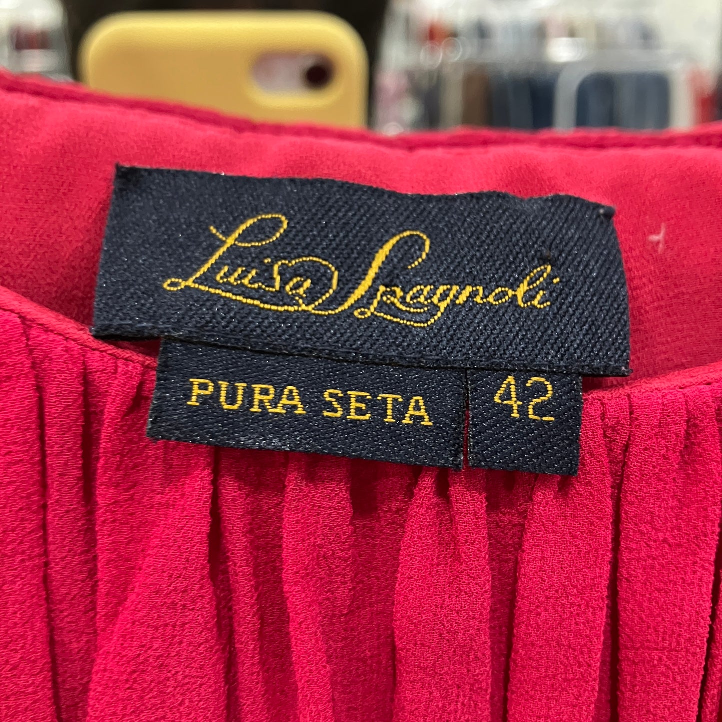 Red fabric with 'Luca Spagnoli' label on a blurred background
