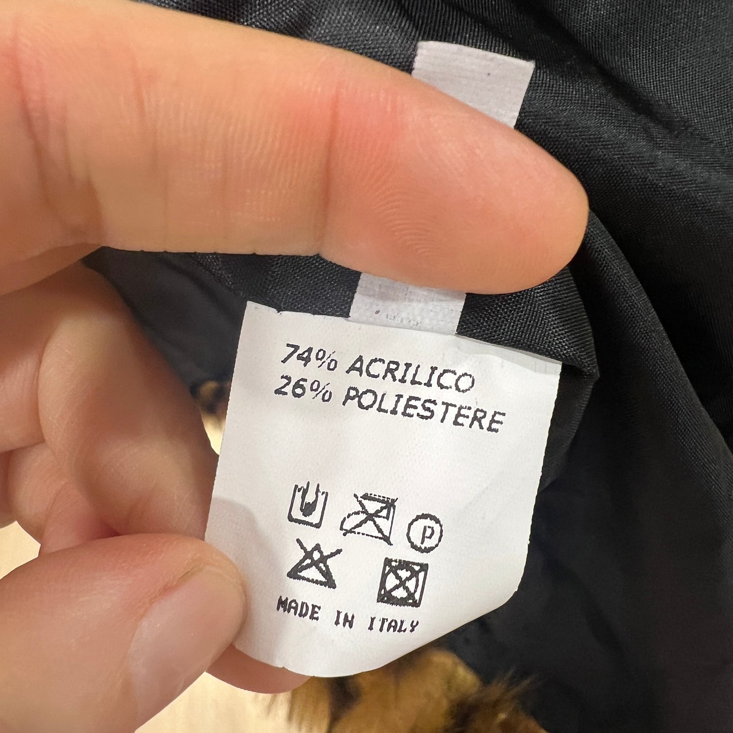 Clothing label with material composition and care instructions held by a hand