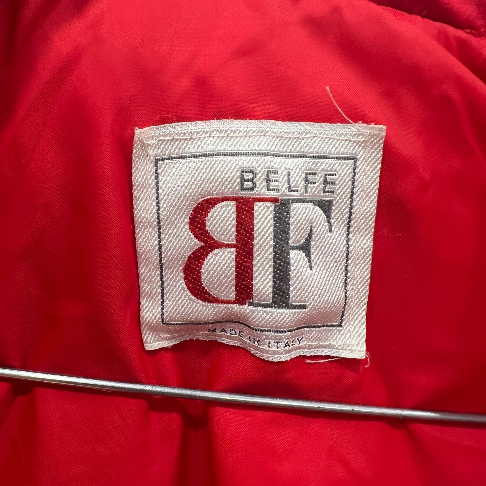 Close-up of a red fabric with a visible brand label on a red background