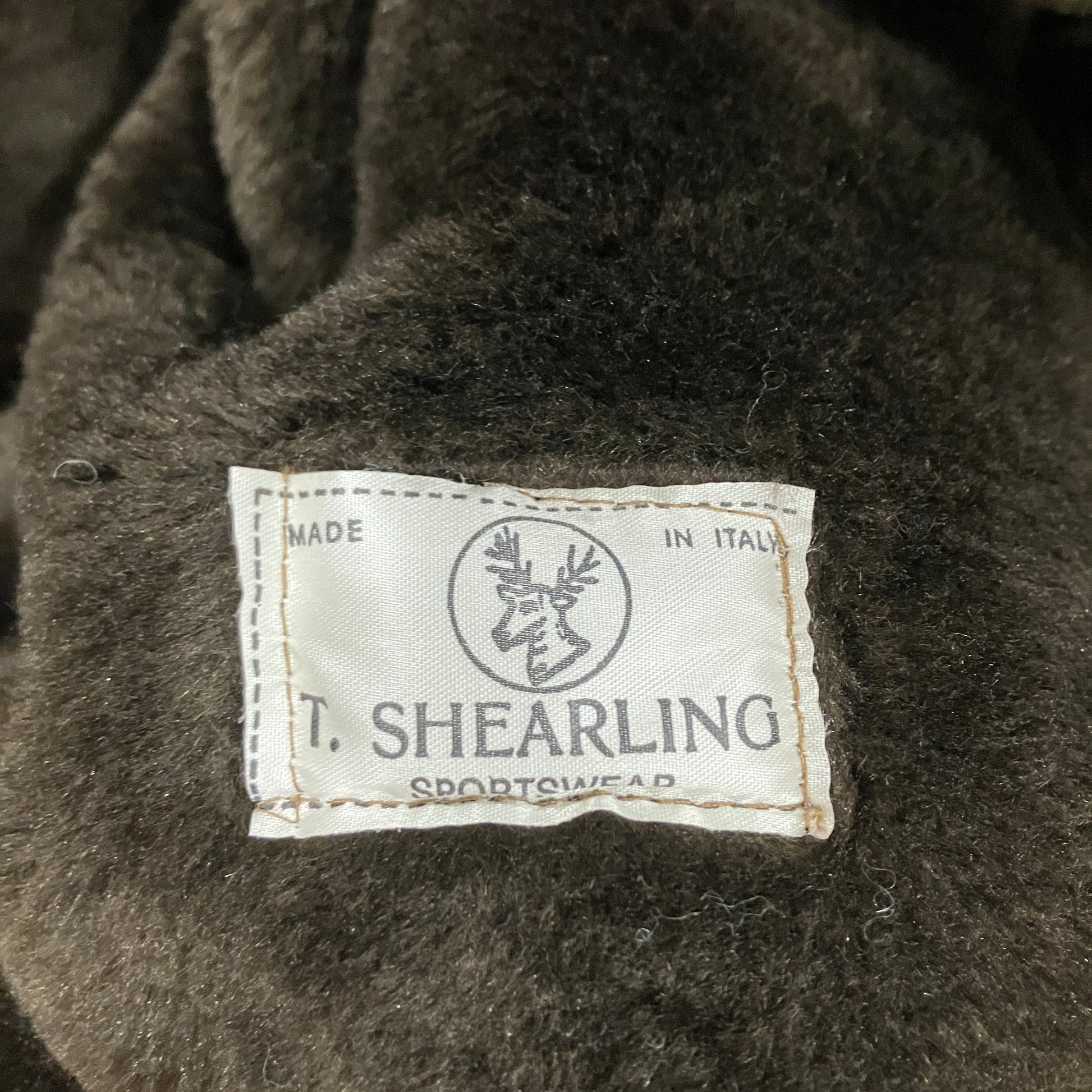 Close-up of a T. Shearling label on a dark brown sheepskin coat