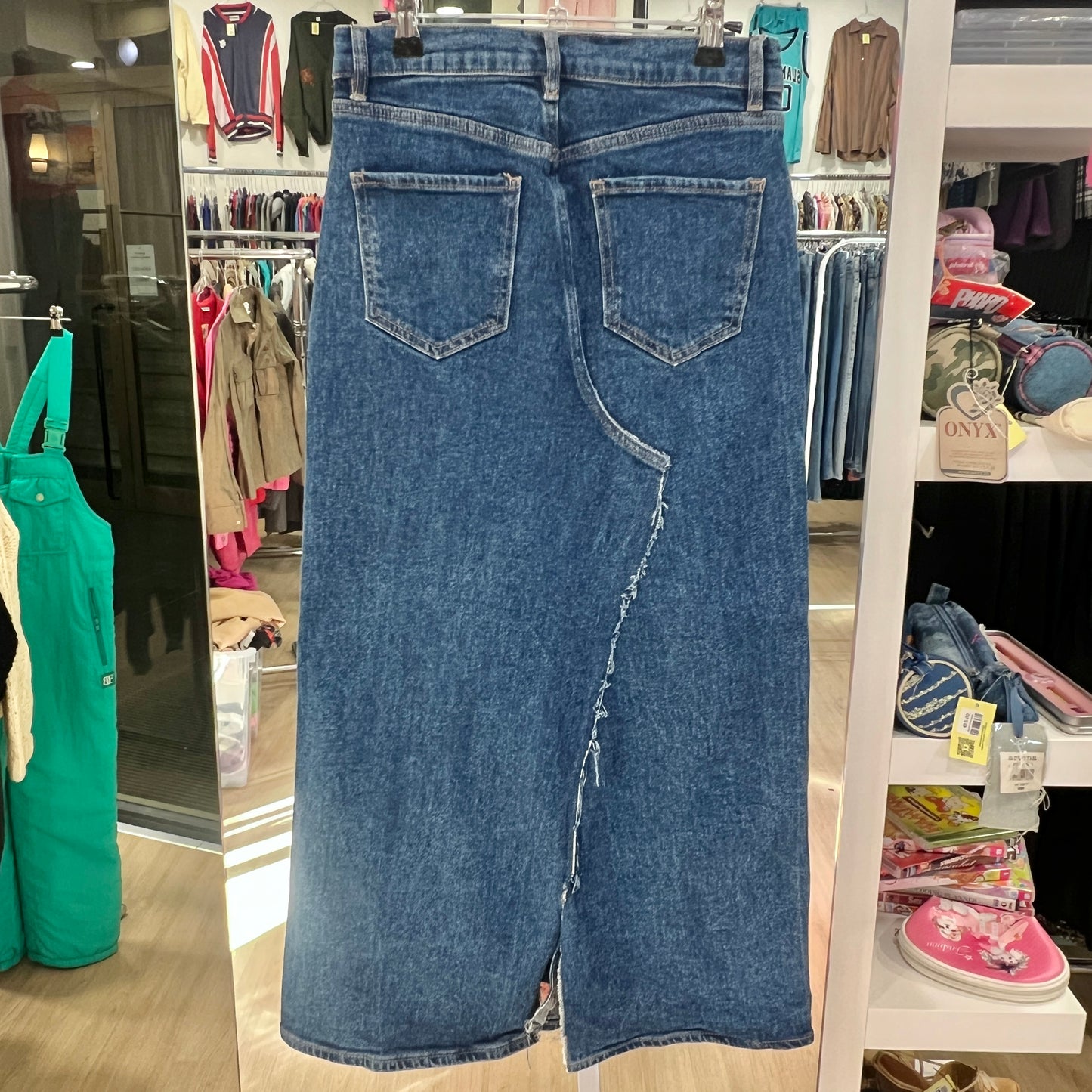 Blue jeans displayed in a store setting with various clothing items in the background