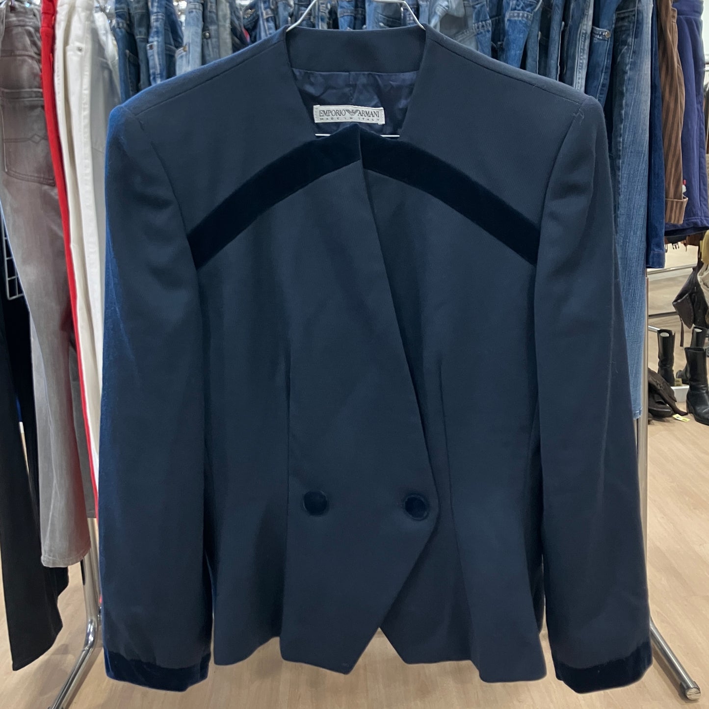 Navy blazer with dark blue accents on a rack in a store setting