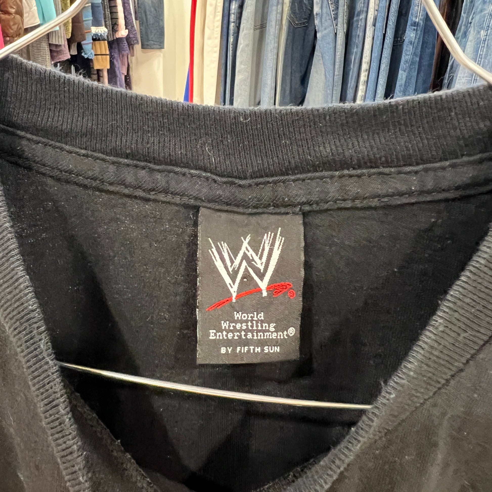 Black shirt with WWE label on a rack of clothes