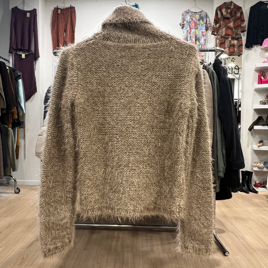 Beige fuzzy cardigan on a hanger in a clothing store setting