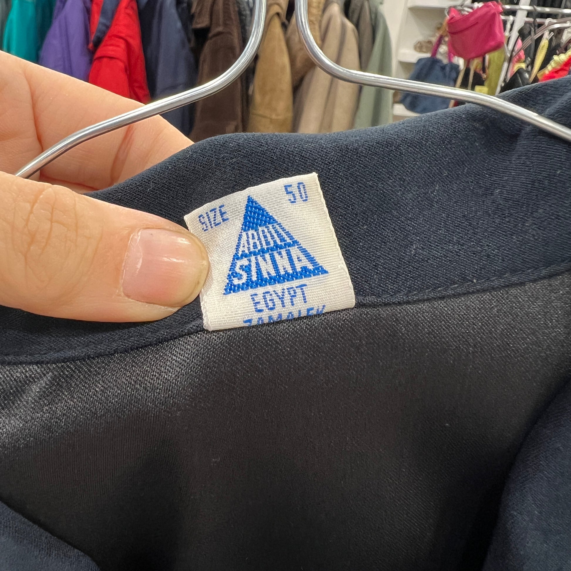 Clothing tag on a dark fabric with visible brand name and size information
