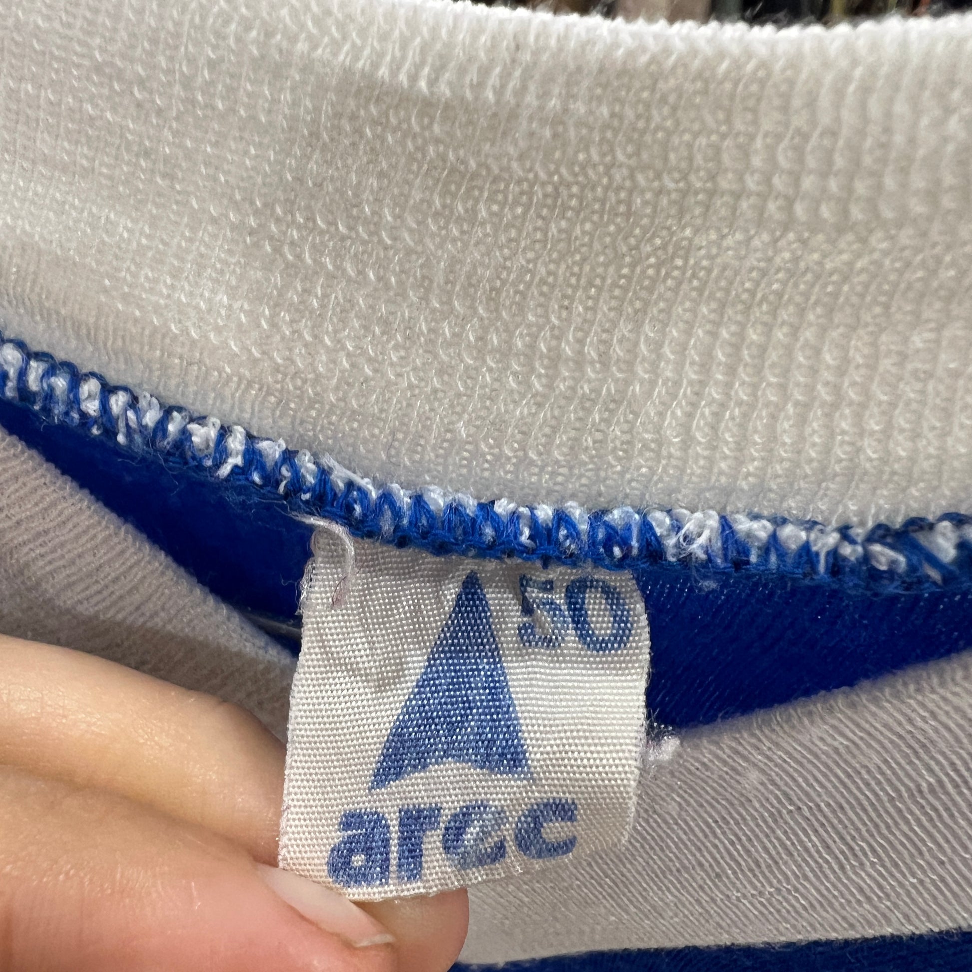Close-up of a fabric tag with a logo and text on a white and blue striped background