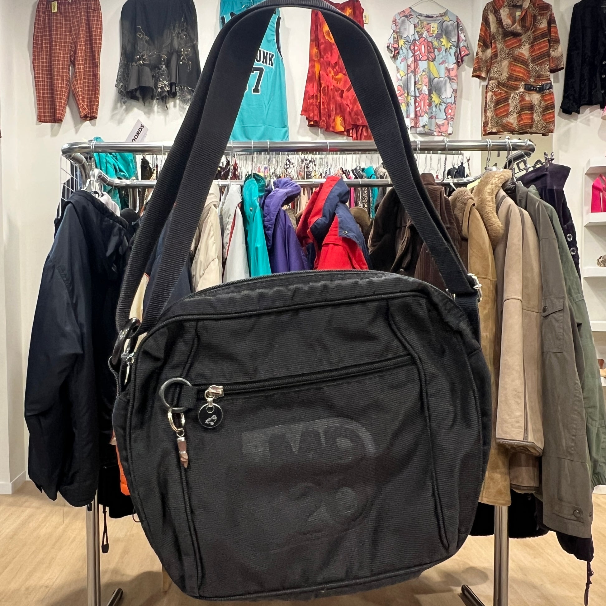 Black bag with 'MD 20' branding in a clothing store setting