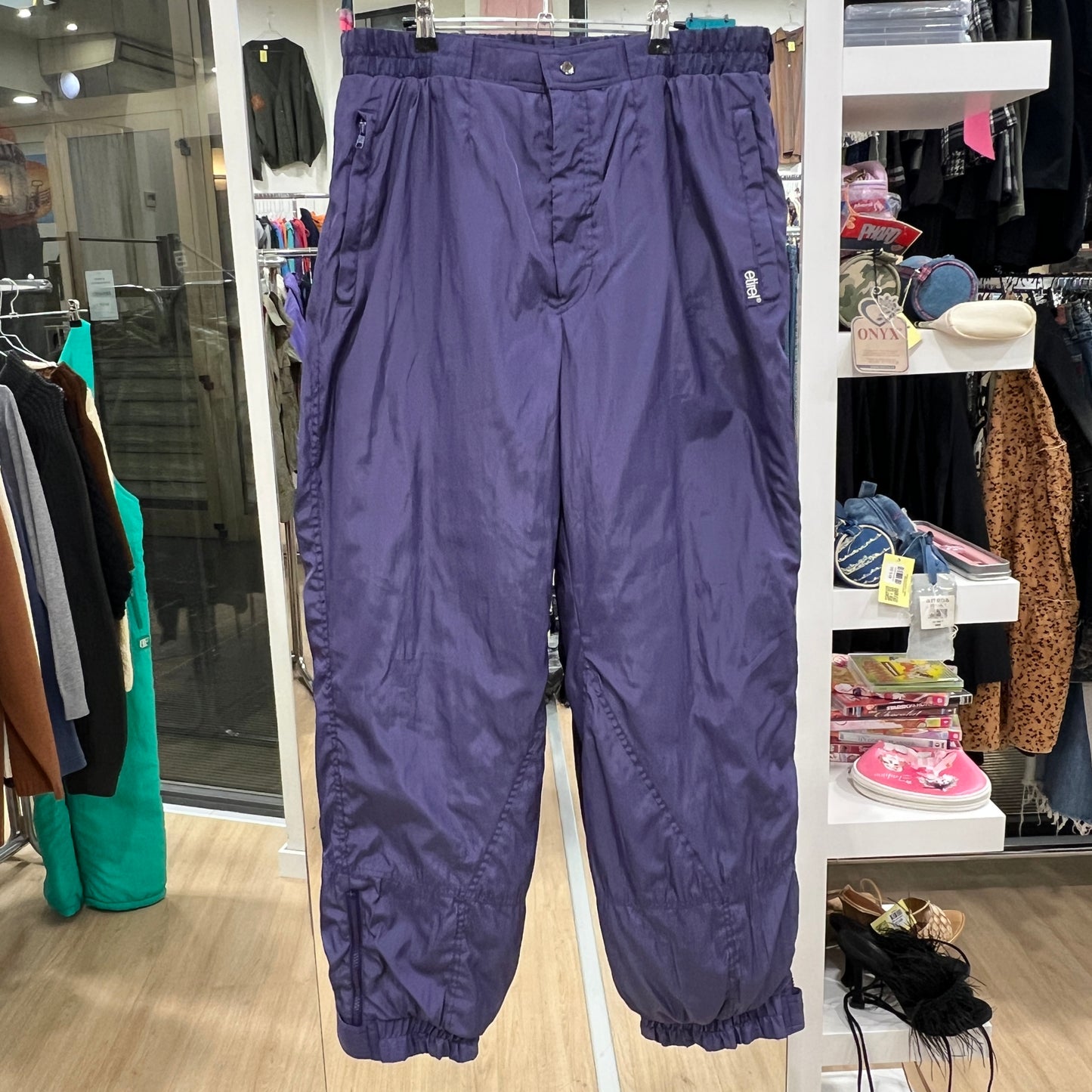Purple pants hanging in a store with clothing racks and shelves in the background