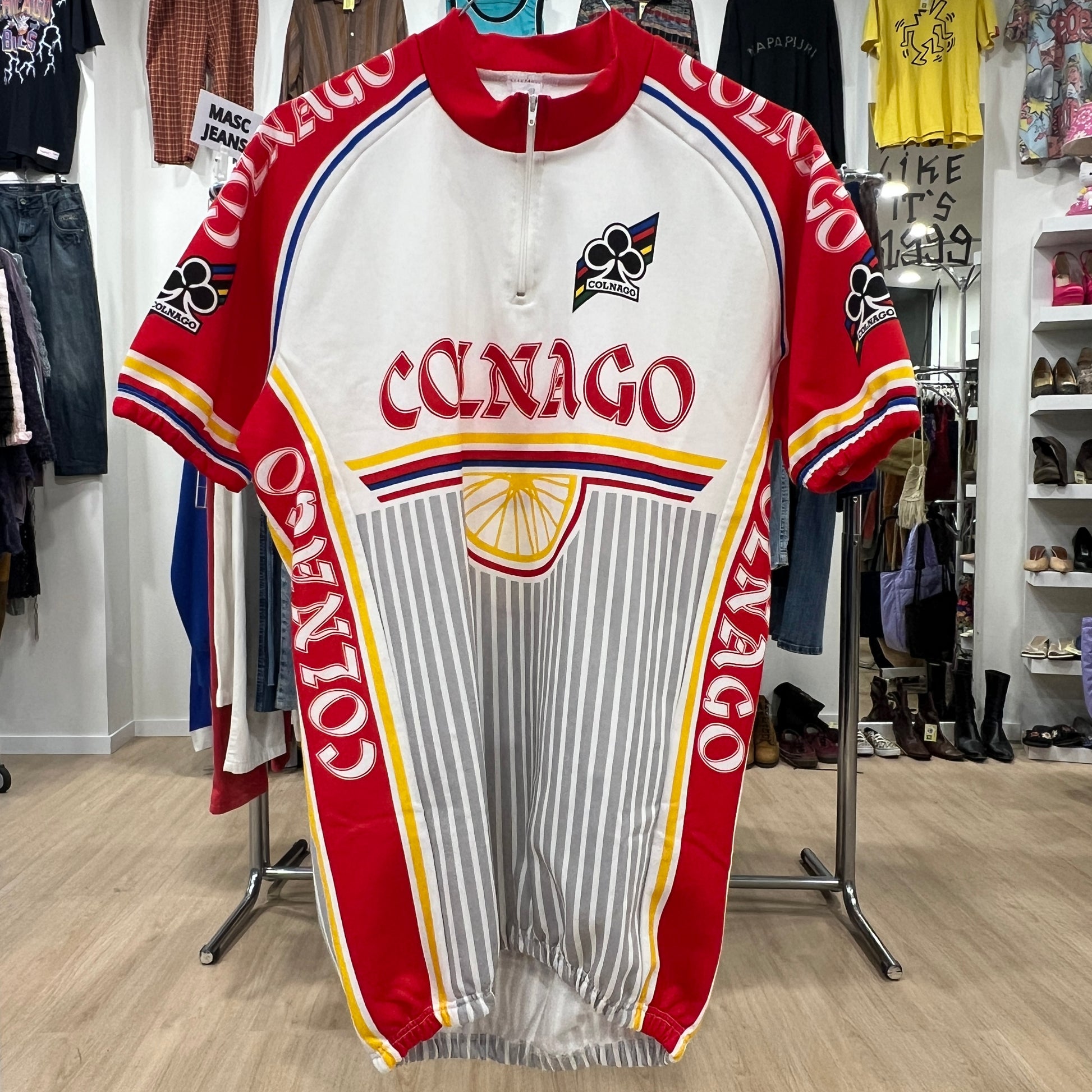 Red and white cycling jersey with 'Colnago' branding in a store setting
