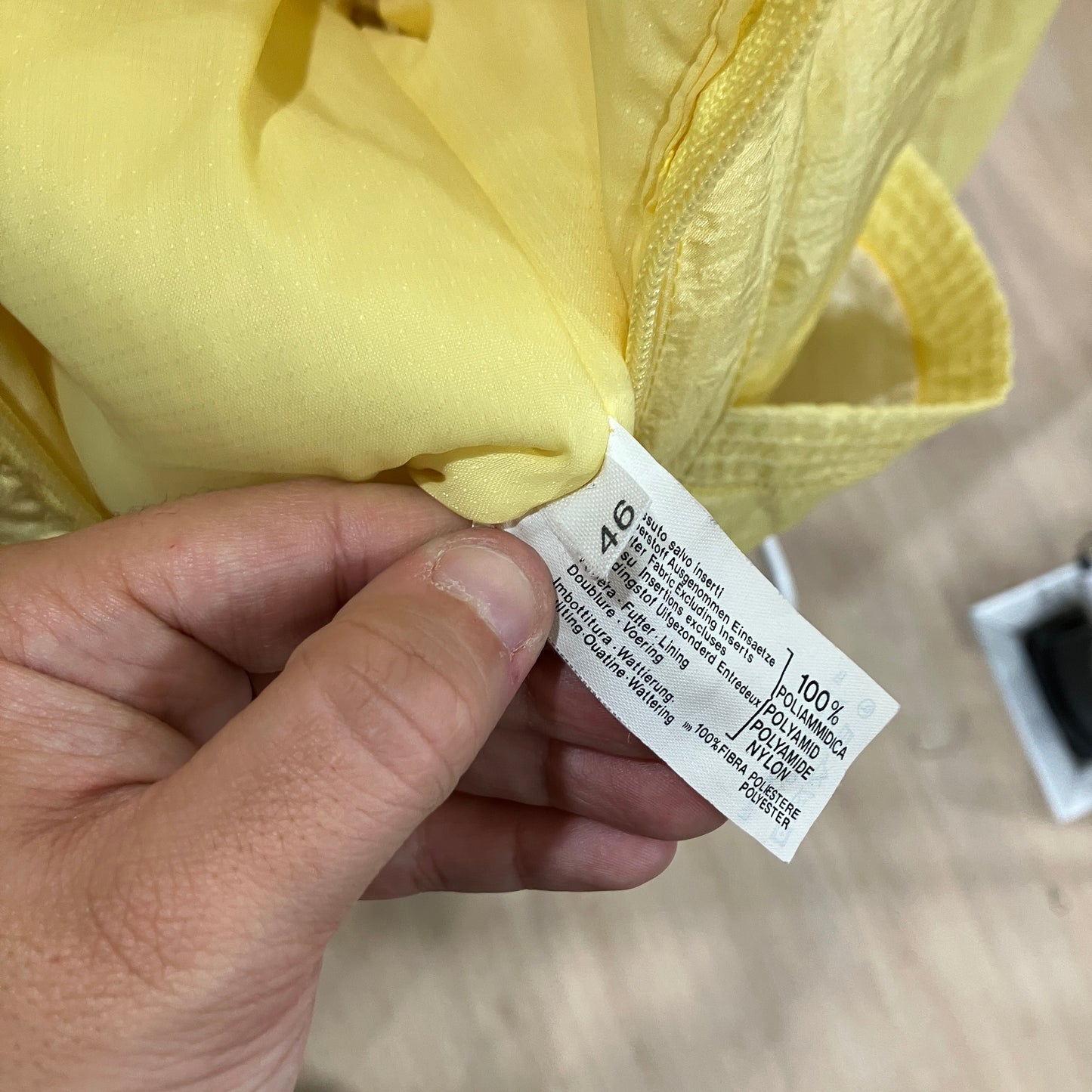 Hand holding a yellow garment with a label showing fabric composition