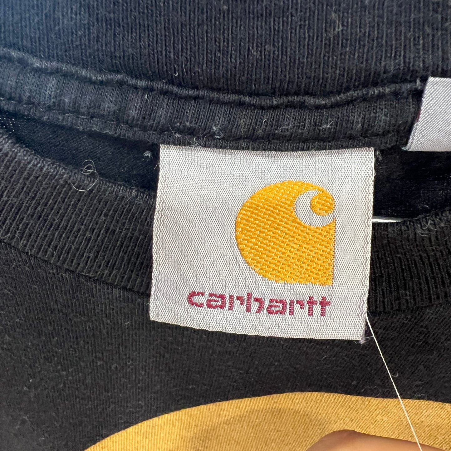 Close-up of a Carhartt label on a black garment with yellow logo