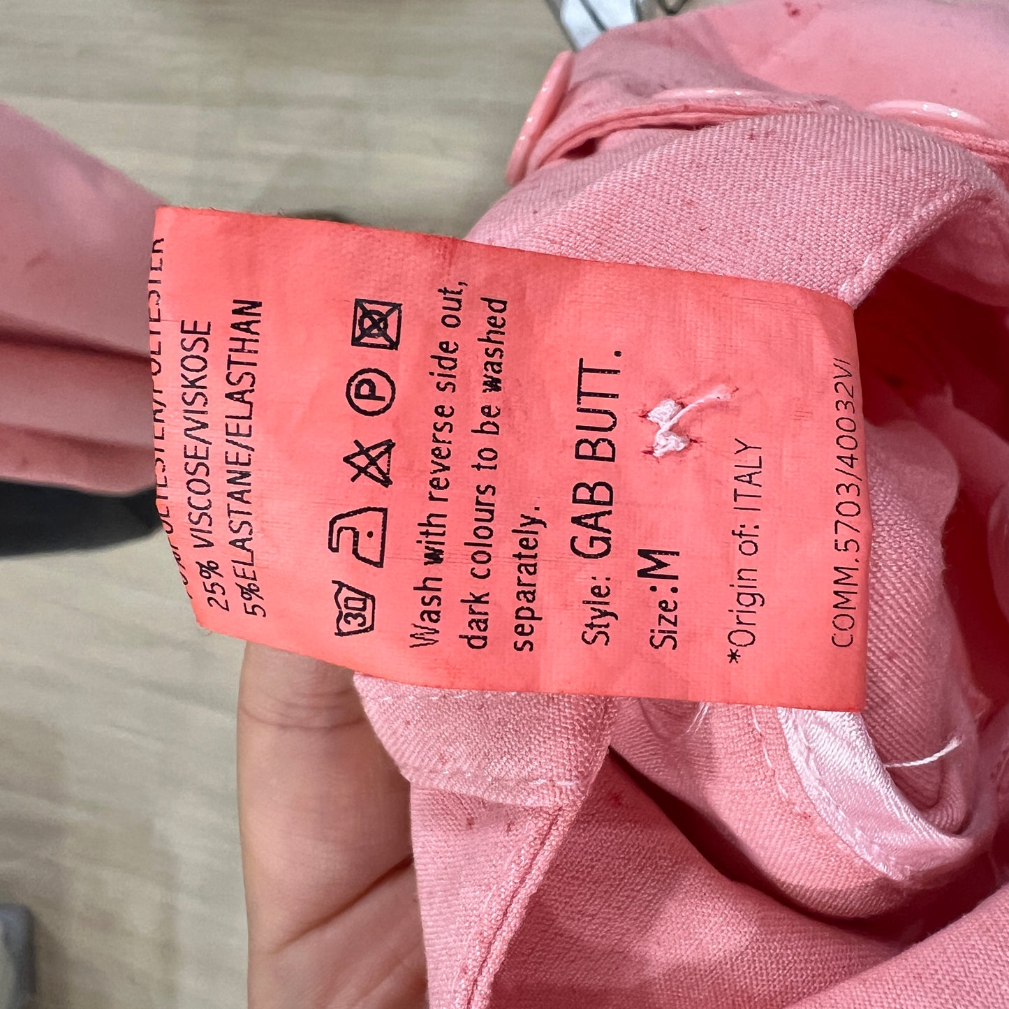 Pink garment tag with text on a pink fabric background