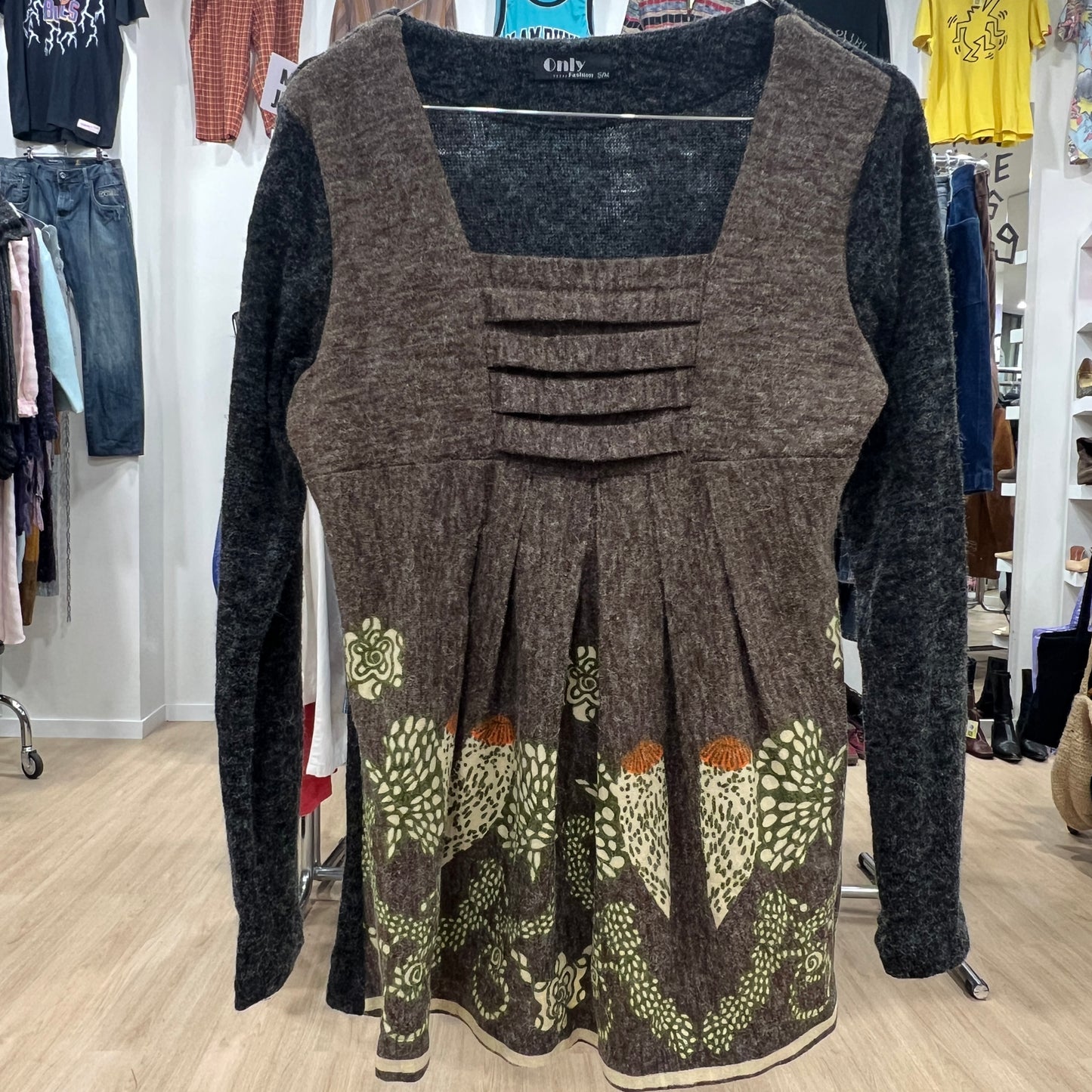 Brown patterned dress with long sleeves in a store setting