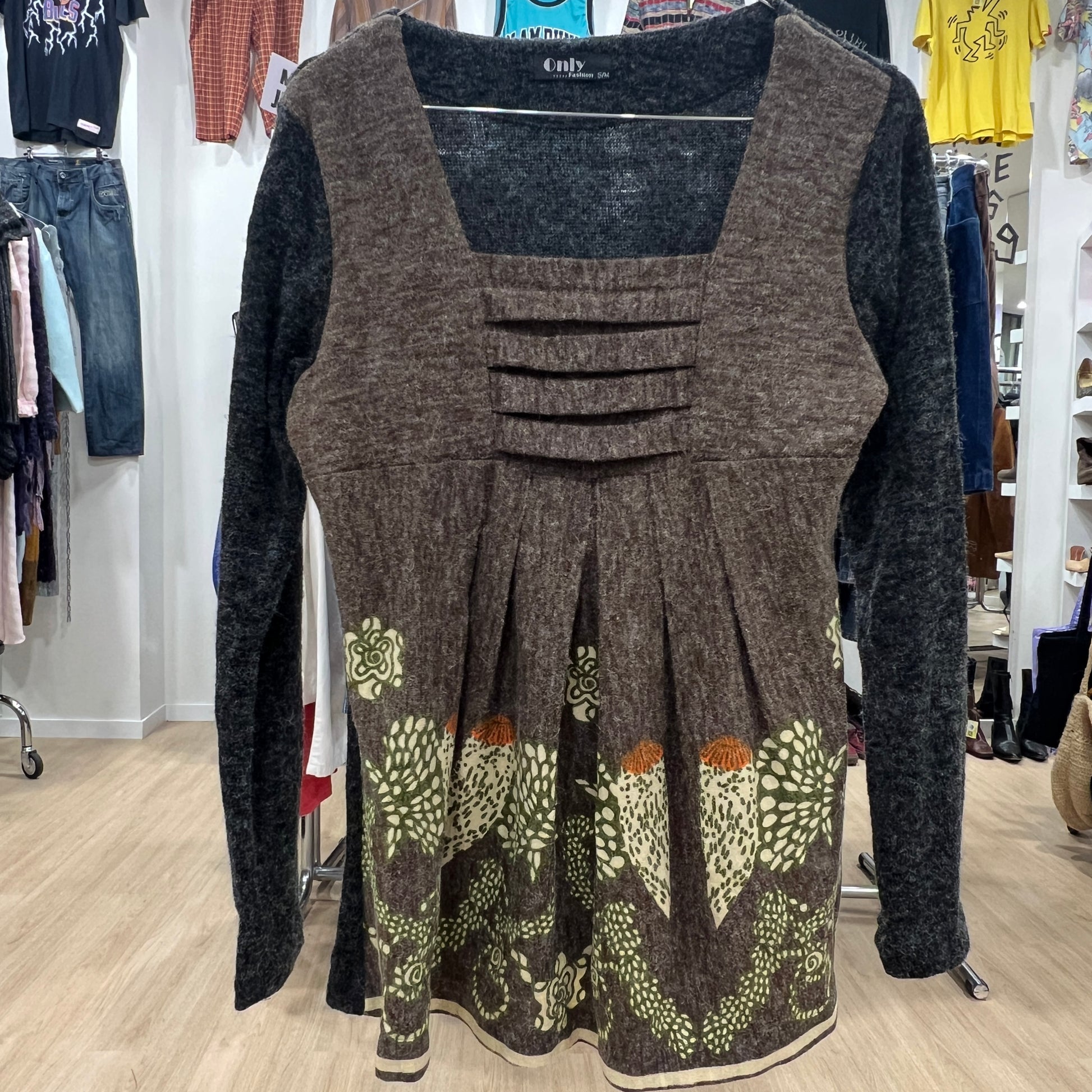 Brown patterned dress with long sleeves in a store setting