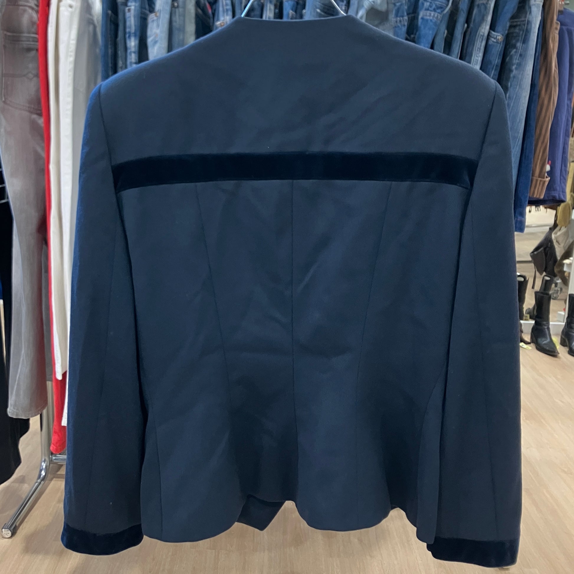 Navy blue jacket with a horizontal stripe on a hanger against a clothing store background