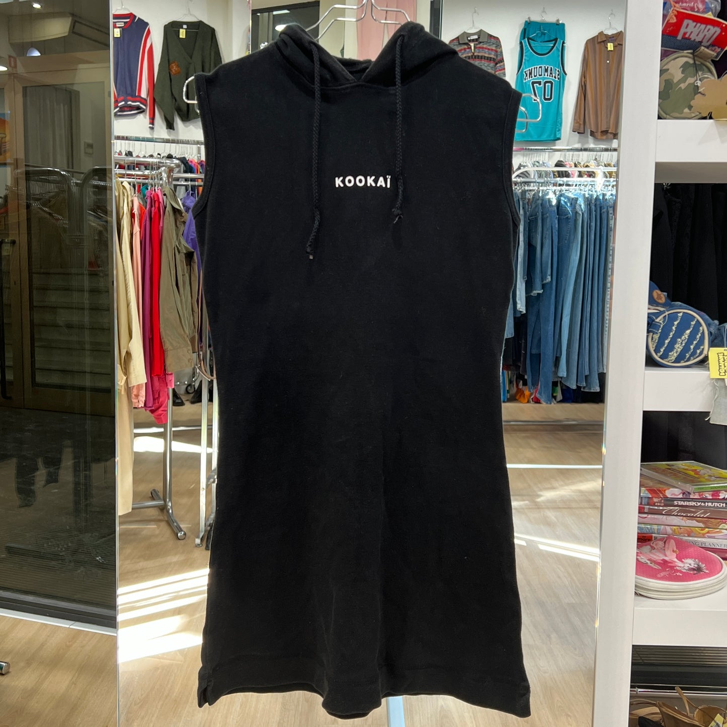 Black sleeveless hoodie with 'Kookai' logo in a store setting