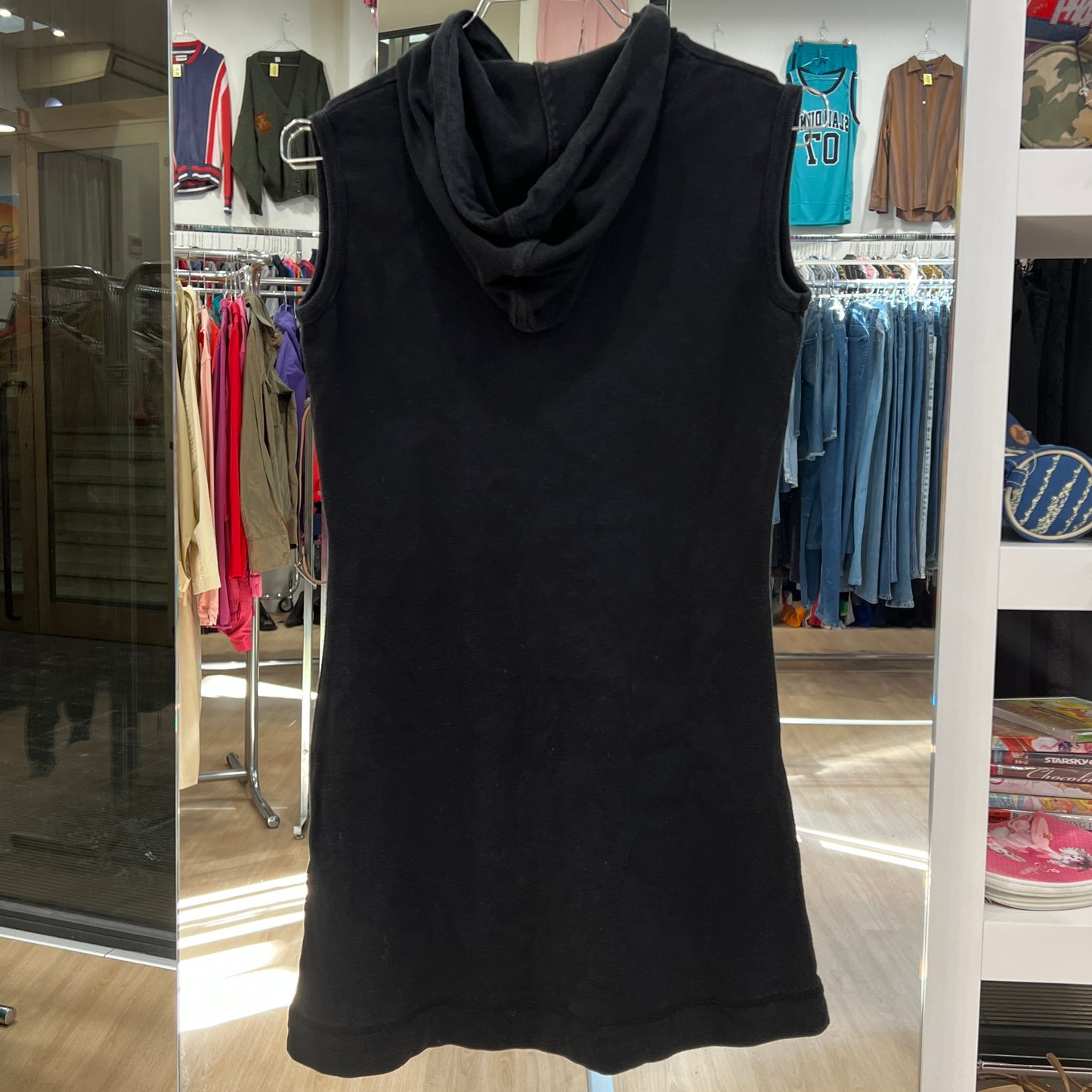 Black sleeveless dress with a hood on a hanger in a store setting