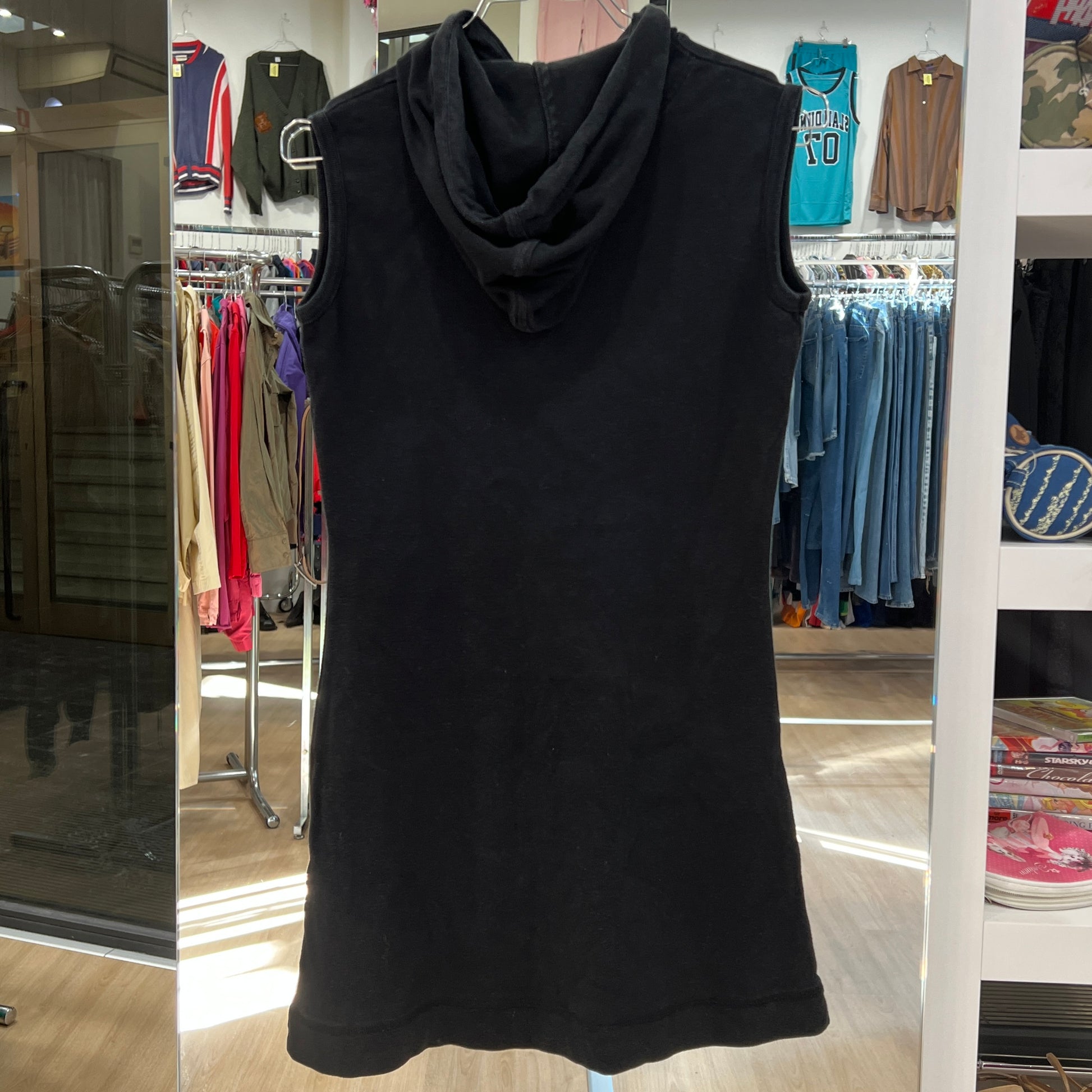 Black sleeveless dress with a hood on a hanger in a store setting