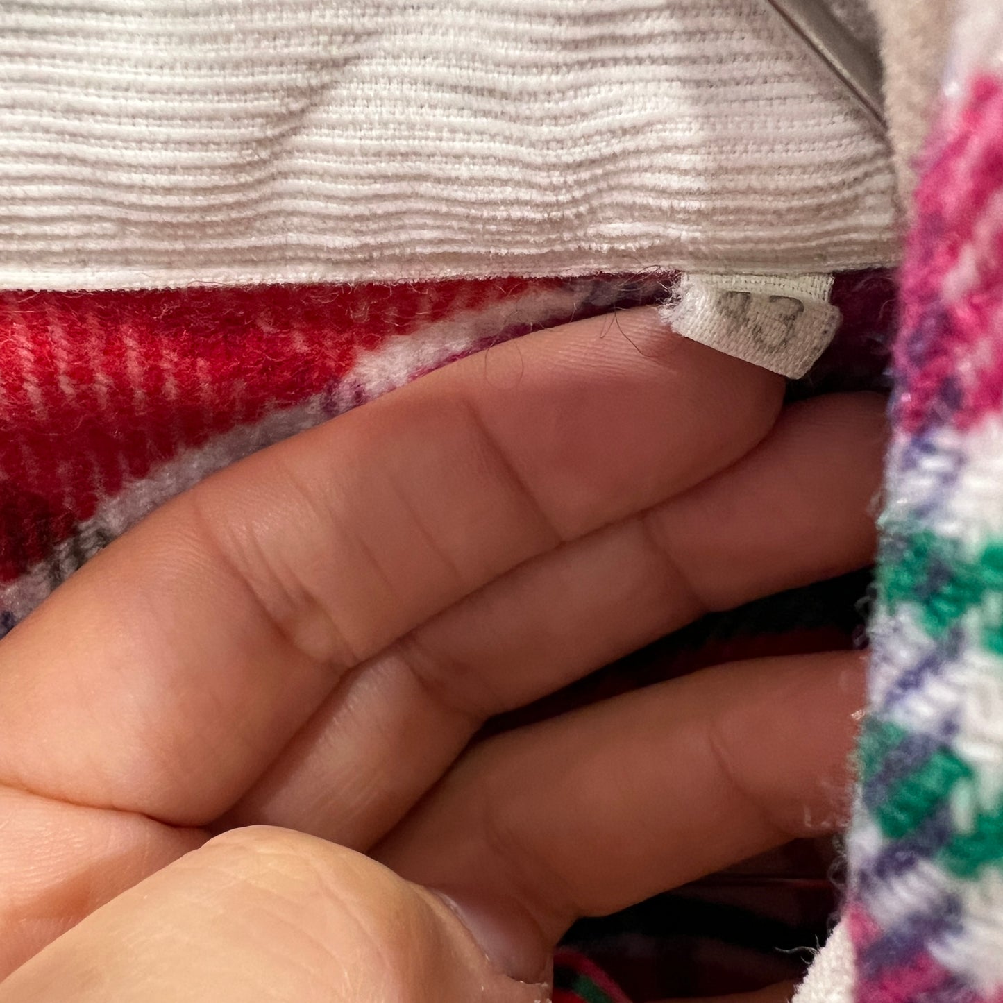 Close-up of a hand holding fabric with a visible brand label
