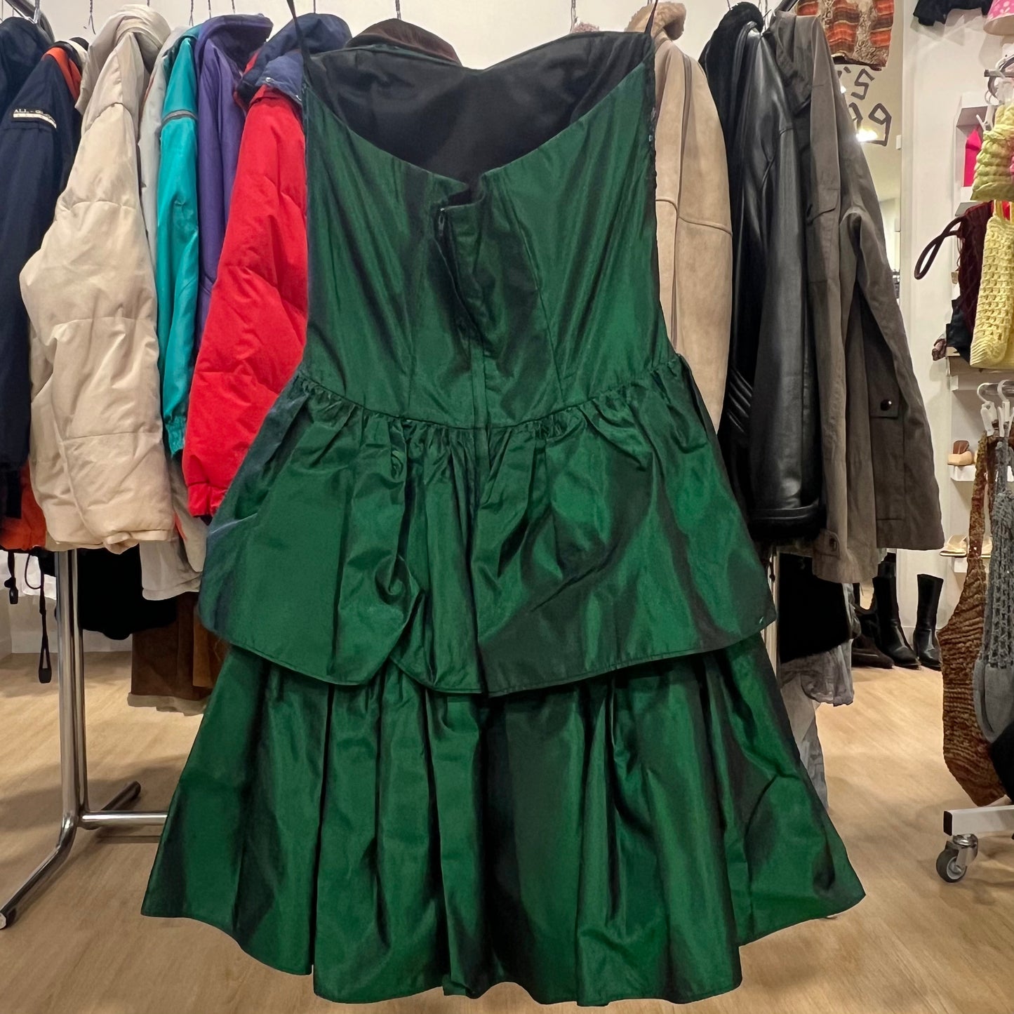 Green dress hanging on a rack with other clothing items in a store setting