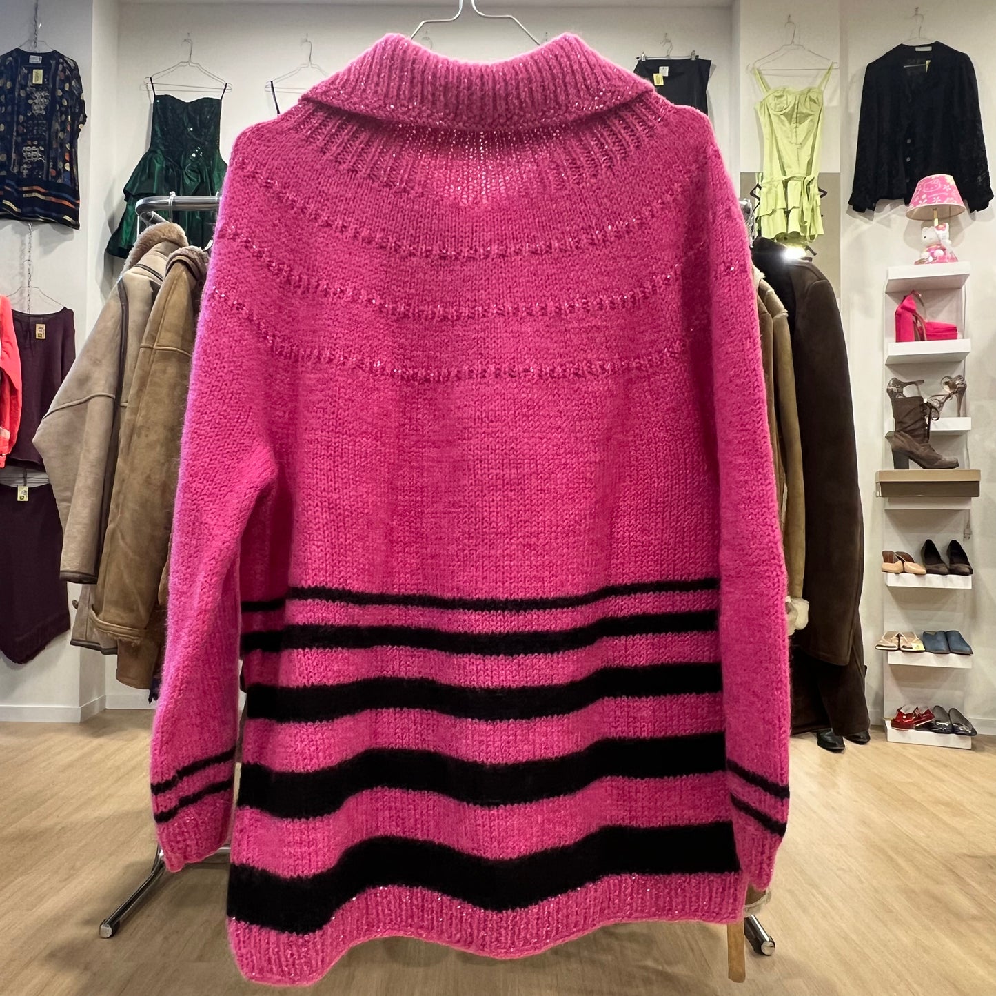 Pink sweater with black stripes hanging on a rack in a clothing store