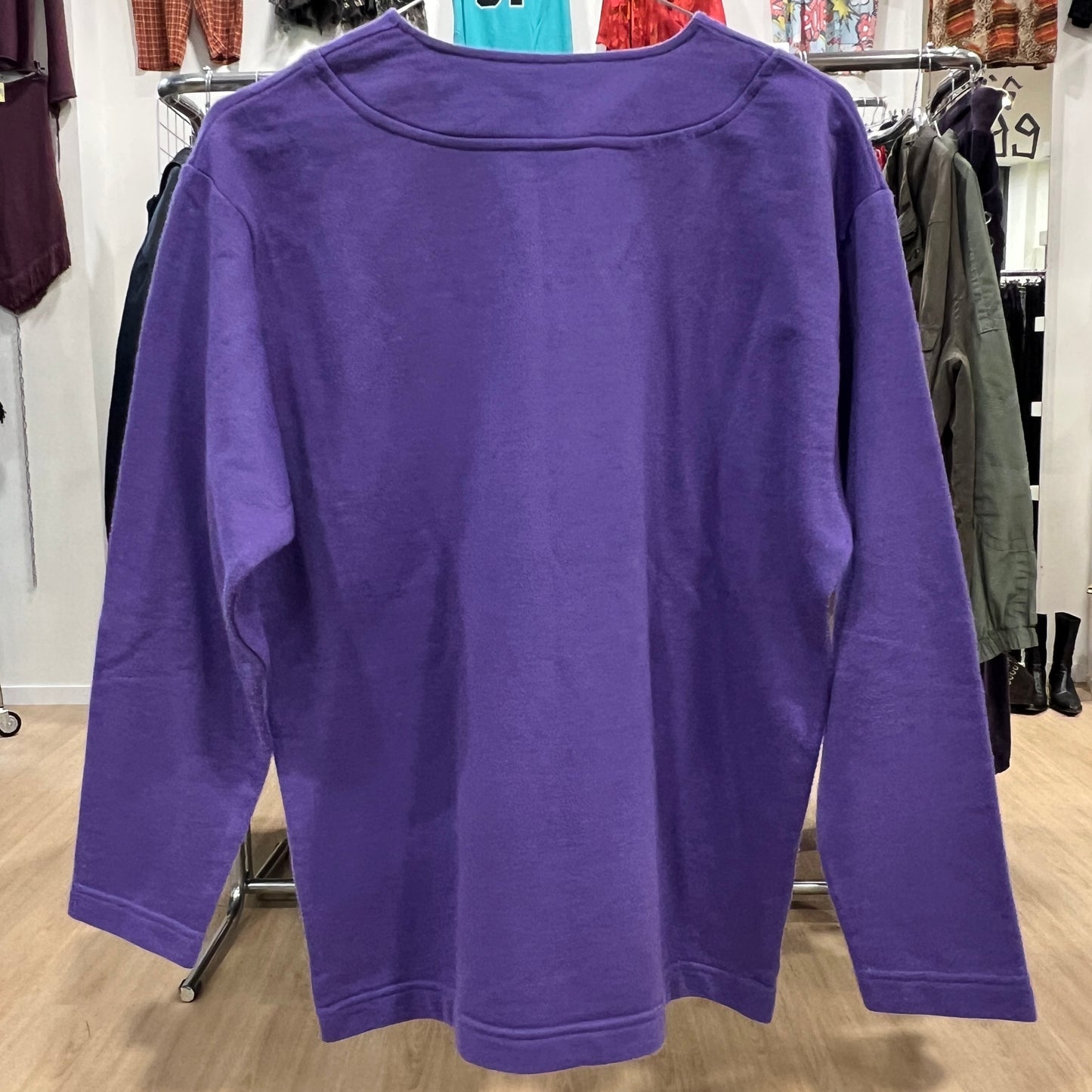 Purple sweatshirt hanging on a rack in a store setting