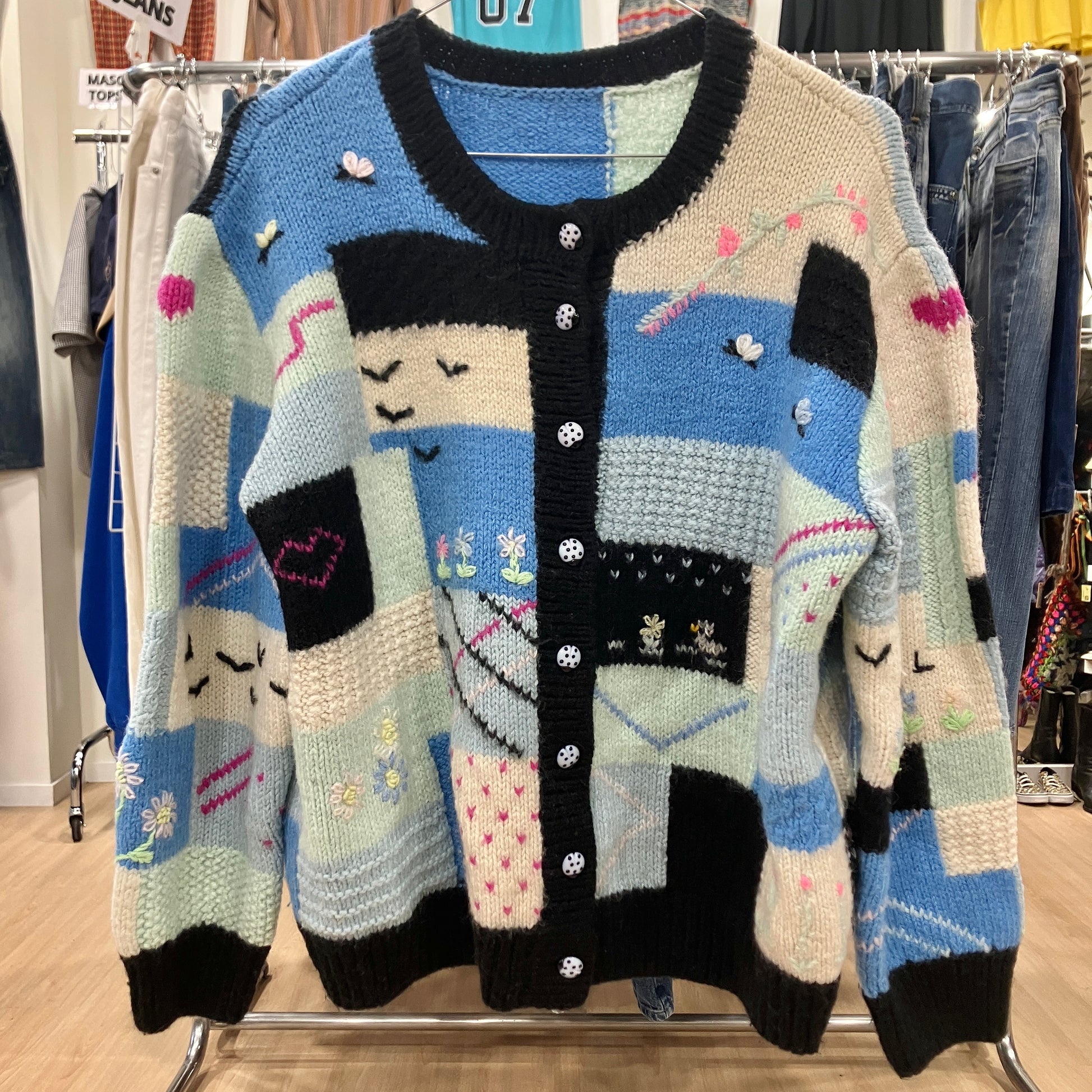 Colorful knitted cardigan with patchwork design on a rack in a store