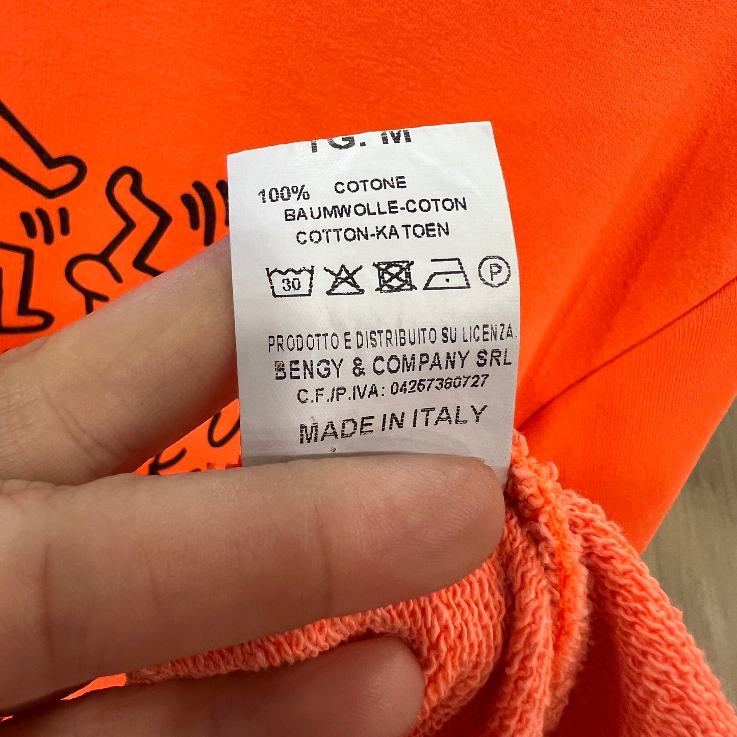 Clothing label on an orange garment with visible text and symbols