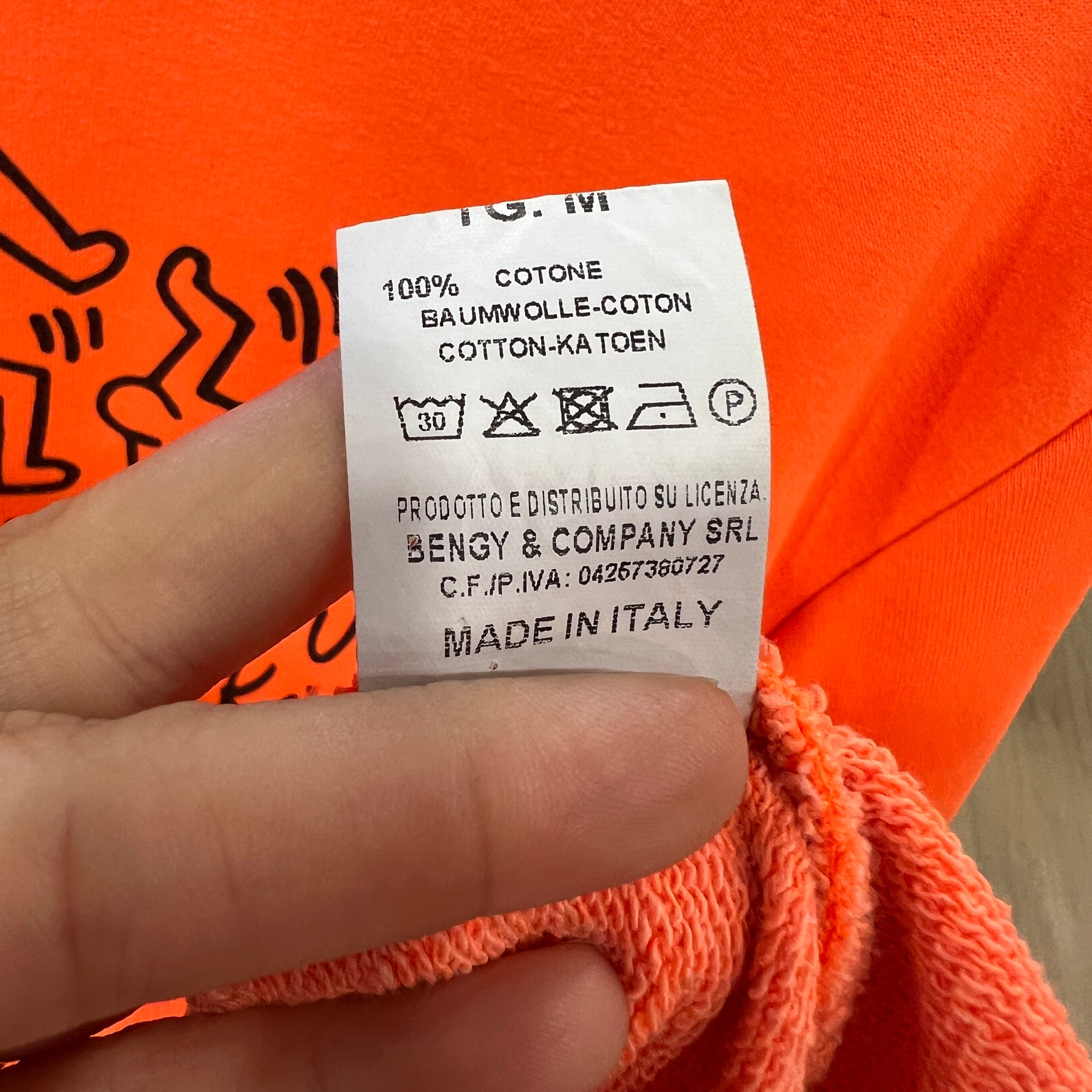 Clothing label on an orange garment with visible text and symbols