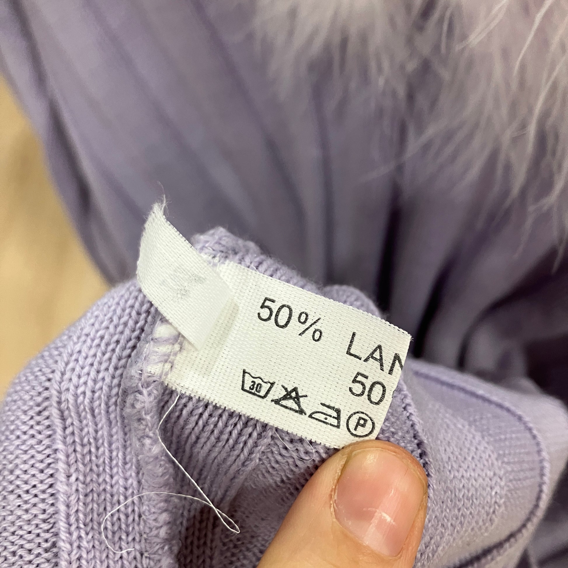 Clothing label on a purple garment with visible text and symbols