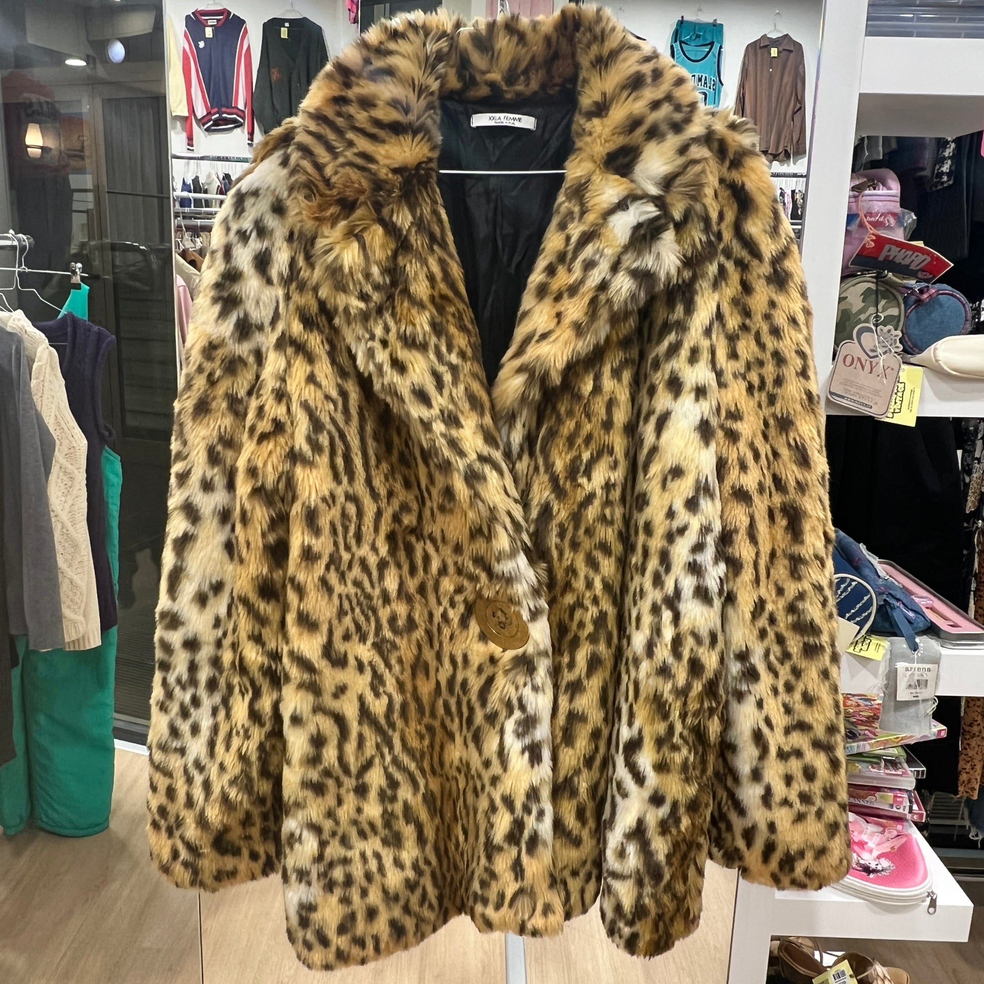 Leopard print fur coat in a store setting with clothing racks and products in the background