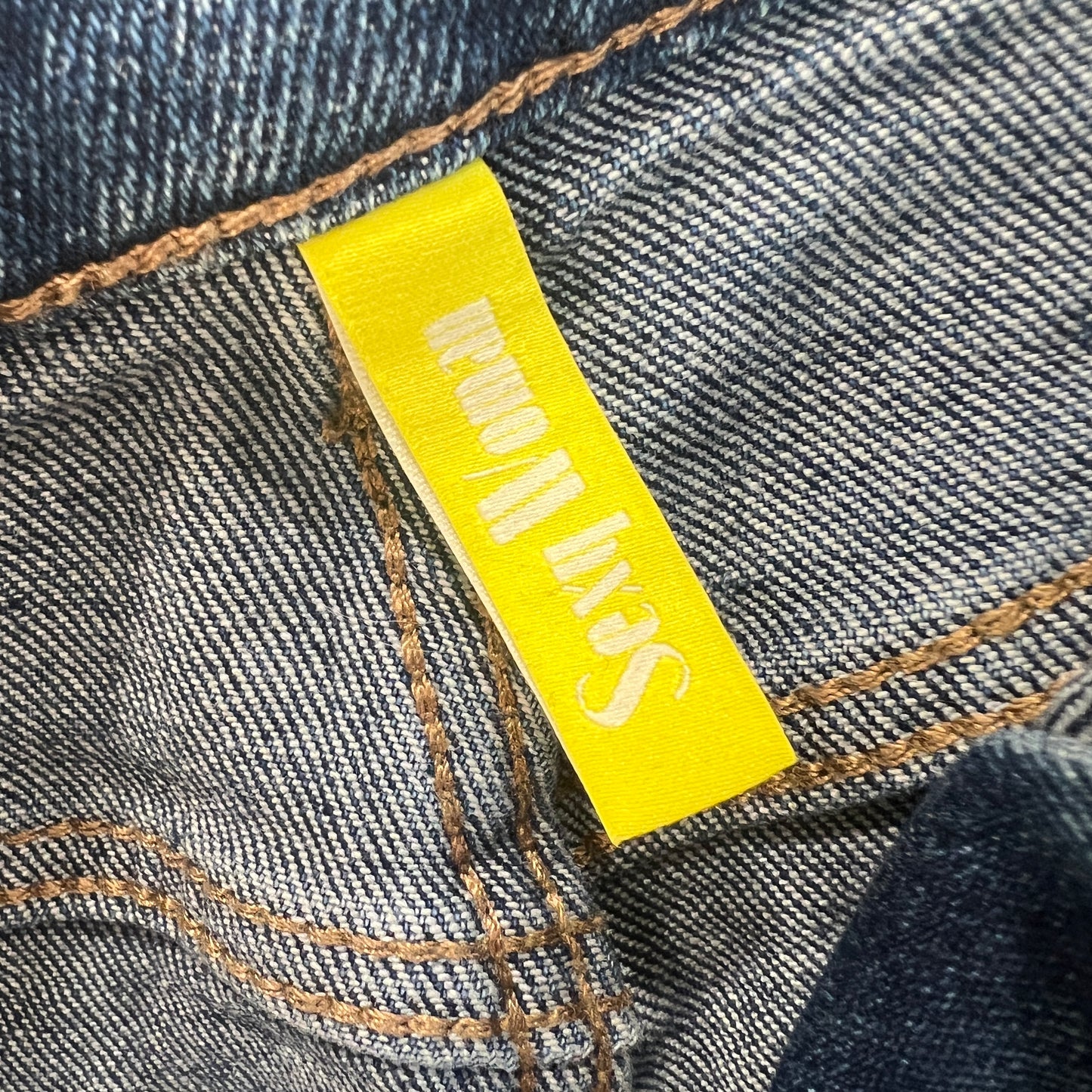 Close-up of a yellow label on denim fabric with 'Sexy Woman' branding