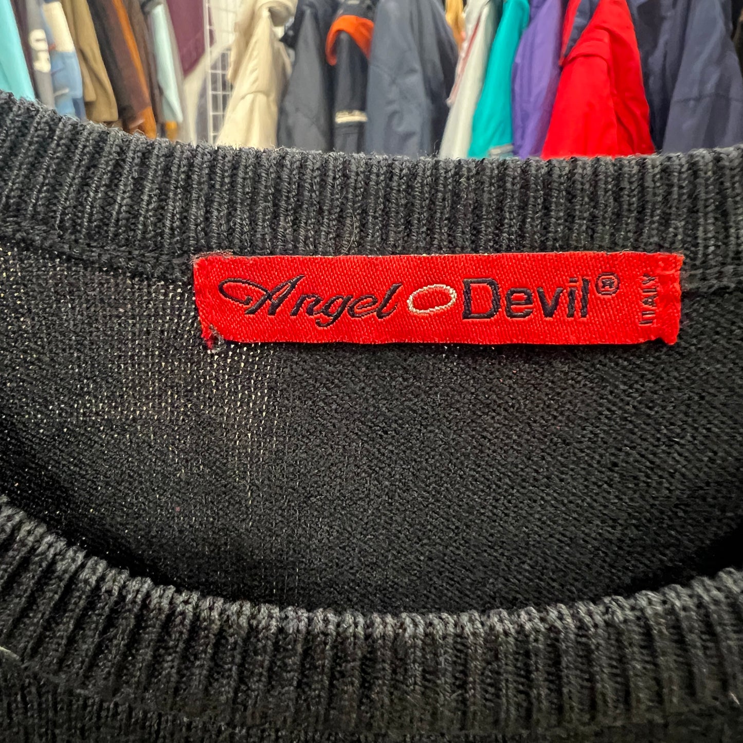 Black fabric with a red 'Angel Devil' label against a background of hanging clothes