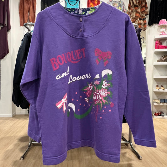Purple sweatshirt with floral design and text in a store setting