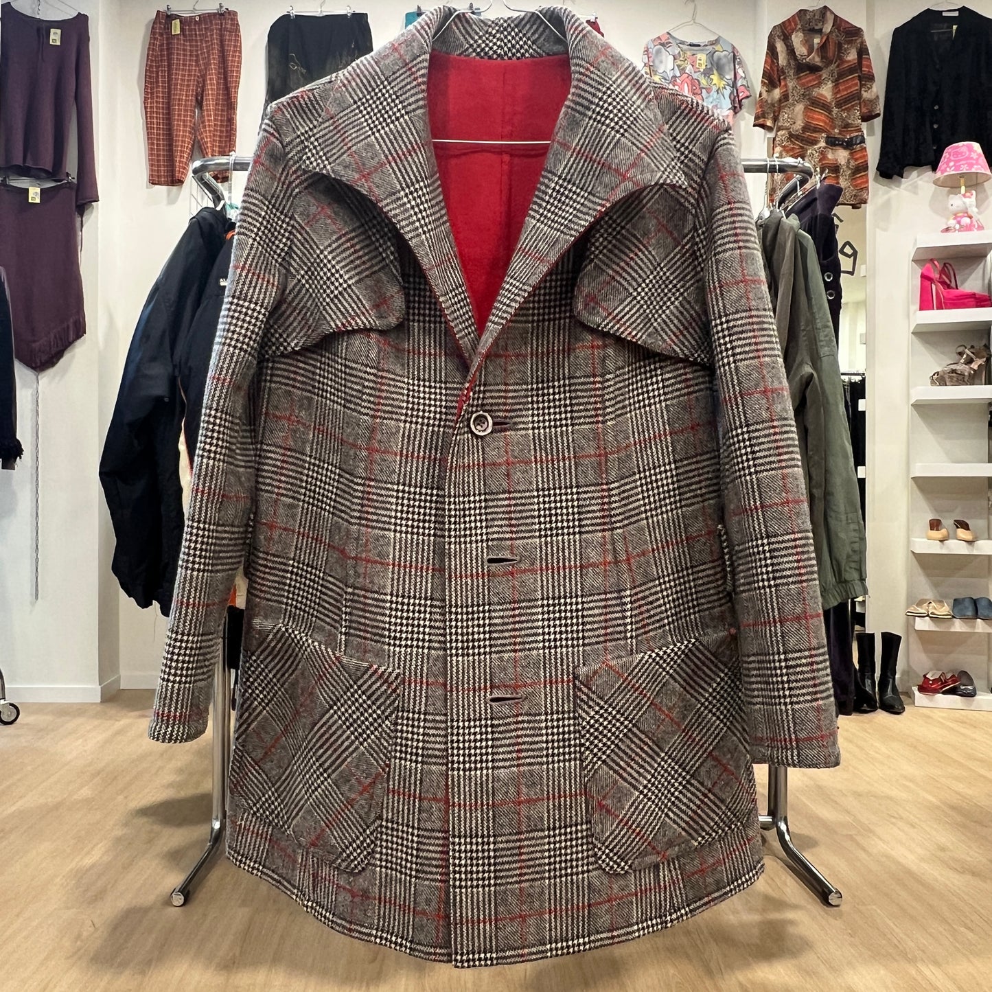 Plaid coat on a rack in a store setting with other clothing items in the background