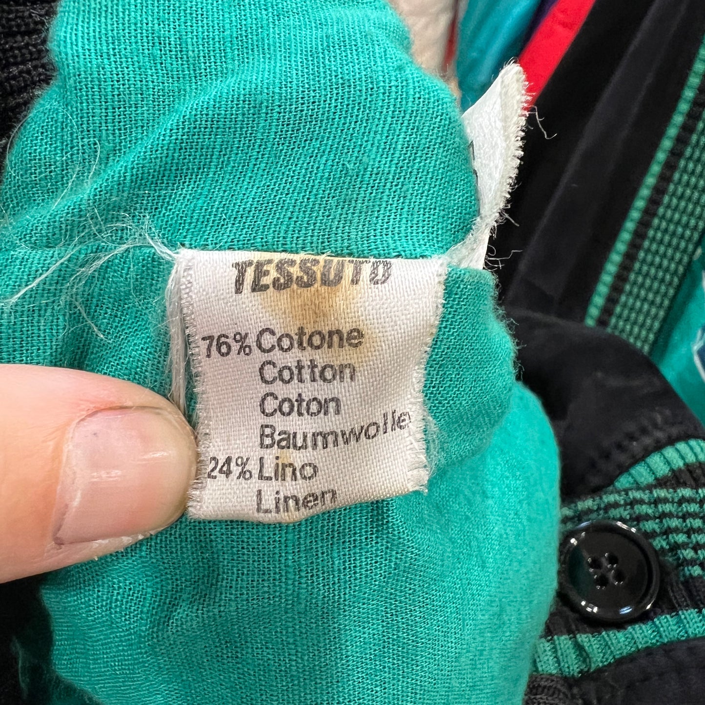 Clothing label on teal fabric with text indicating material composition